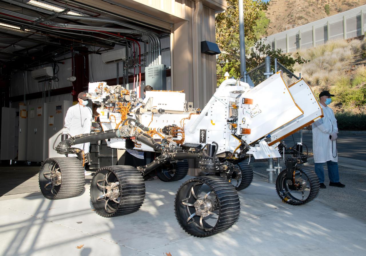 Updated with new features, including additional mobility software and the bulk of the sample caching system, the Earthly twin of NASA's Perseverance Mars rover arrives at the Mars Yard garage at the agency's Jet Propulsion Laboratory on Oct. 29, 2021. The vehicle is generically referred to as a vehicle system test bed but goes by the name OPTIMISM (short for Operational Perseverance Twin for Integration of Mechanisms and Instruments Sent to Mars).  As with vehicle system test beds for other Mars rovers, OPTIMISM is used to test moves and scenarios in the Mars Yard's simulated Red Planet landscape to help ensure that its twin on Mars can safely execute the commands sent by Earth-bound controllers. The tests could also potentially reveal unexpected problems Perseverance might encounter. With longer drives in Perseverance's near future, another job for OPTIMISM will involve presenting new challenges to the rover's autonomous navigation system, or AutoNav.  A key objective for Perseverance's mission on Mars is astrobiology, including the search for signs of ancient microbial life. The rover will characterize the planet's geology and past climate, pave the way for human exploration of the Red Planet, and be the first mission to collect and cache Martian rock and regolith (broken rock and dust).  Subsequent NASA missions, in cooperation with ESA (European Space Agency), would send spacecraft to Mars to collect these sealed samples from the surface and return them to Earth for in-depth analysis.  The Mars 2020 Perseverance mission is part of NASA's Moon to Mars exploration approach, which includes Artemis missions to the Moon that will help prepare for human exploration of the Red Planet.  https://photojournal.jpl.nasa.gov/catalog/PIA24528
