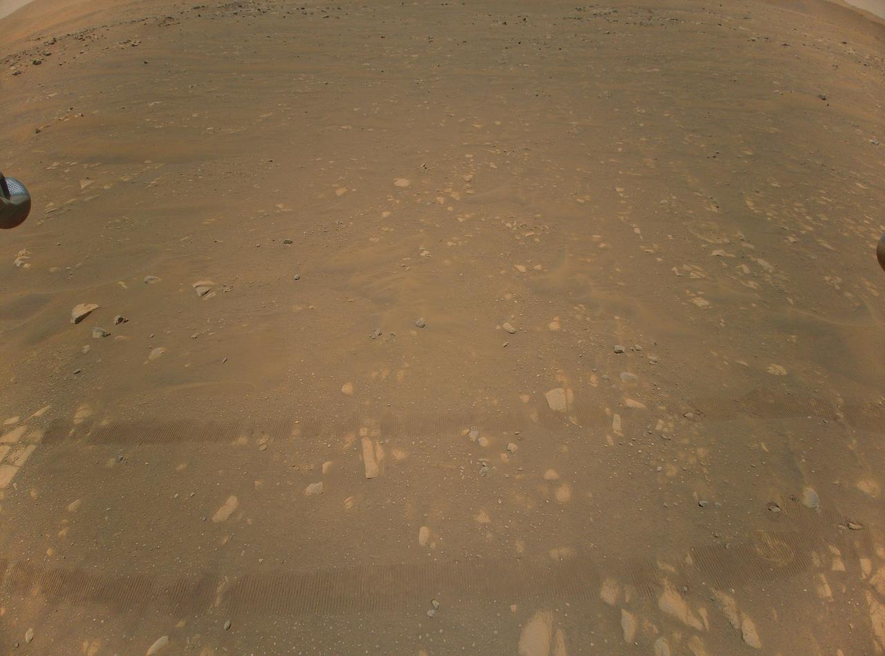 This is the third color image taken by NASA's Ingenuity helicopter. It was snapped on the helicopter's second flight, on April 22, 2021, from an altitude of about 17 feet (5.2 meters). Tracks made by NASA's Perseverance Mars rover can be seen as well.  https://photojournal.jpl.nasa.gov/catalog/PIA24621