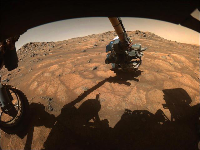 The robotic arm on NASA's Perseverance rover reached out to examine rocks in an area on Mars nicknamed the "Cratered Floor Fractured Rough" area in this image captured on July 10, 2021 (the 138th sol, or Martian day, of its mission). The image was taken by one of the rover's hazard cameras. An additional set of images from July 10-12 have been compiled into a GIF.  Scientists are particularly interested in the flat rocks that appear light in color (nicknamed "paver rocks"). This image was processed to enhance contrast.  A key objective for Perseverance's mission on Mars is astrobiology, including the search for signs of ancient microbial life. The rover will characterize the planet's geology and past climate, pave the way for human exploration of the Red Planet, and be the first mission to collect and cache Martian rock and regolith (broken rock and dust).  Subsequent NASA missions, in cooperation with ESA (European Space Agency), would send spacecraft to Mars to collect these sealed samples from the surface and return them to Earth for in-depth analysis.  The Mars 2020 Perseverance mission is part of NASA's Moon to Mars exploration approach, which includes Artemis missions to the Moon that will help prepare for human exploration of the Red Planet.  Movie available at https://photojournal.jpl.nasa.gov/catalog/PIA24748