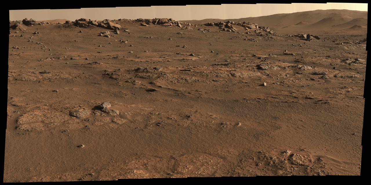 NASA's Perseverance Mars rover used its Mastcam-Z camera system to create this panorama of its first drill site. Scientists will be looking for a rock to drill somewhere in this.  Perseverance's team has nicknamed this region the "Crater Floor Fractured Rough" unit. The flat, light-colored stones are informally referred to as "paver rocks" and will be the first type from which Perseverance will collect a sample for planned return to Earth by subsequent missions. Small hills to the south of the rover and the sloping inner walls of the Jezero Crater rim fill the distant background of this view.  The panorama is stitched together from 70 individual images taken on July 28, 2021, the 155th Martian day, or sol, of the mission. This panorama is seen here in natural color.  The Mastcam-Z investigation is led and operated by Arizona State University in Tempe, working in collaboration with Malin Space Science Systems in San Diego, California, on the design, fabrication, testing, and operation of the cameras, and in collaboration with the Neils Bohr Institute of the University of Copenhagen on the design, fabrication, and testing of the calibration targets.  A key objective for Perseverance's mission on Mars is astrobiology, including the search for signs of ancient microbial life. The rover will characterize the planet's geology and past climate, pave the way for human exploration of the Red Planet, and be the first mission to collect and cache Martian rock and regolith (broken rock and dust).  Subsequent NASA missions, in cooperation with ESA (European Space Agency), would send spacecraft to Mars to collect these sealed samples from the surface and return them to Earth for in-depth analysis.  The Mars 2020 Perseverance mission is part of NASA's Moon to Mars exploration approach, which includes Artemis missions to the Moon that will help prepare for human exploration of the Red Planet.  https://photojournal.jpl.nasa.gov/catalog/PIA24765