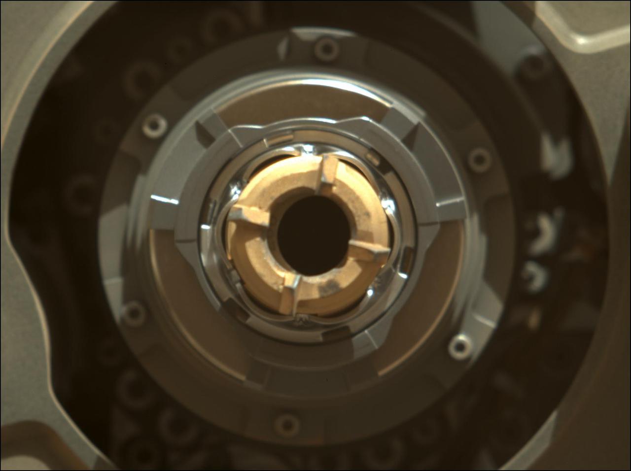 This Mastcam-Z image shows Perseverance's drill with no cored-rock sample evident in the sample tube. The image was taken on Sept. 1, 2021 (the 190th sol, or Martian day, of the mission), after coring – and after a cleaning operation was performed to clear the sample tube's lip of any residual material.  The bronze-colored ring is the coring bit. The half-moon inside the bit is the open end of the sample tube. A portion of the tube's serial number – 266 – can be seen on the left side of tube's rim.  Arizona State University in Tempe leads the operations of the Mastcam-Z instrument, working in collaboration with Malin Space Science Systems in San Diego.  A key objective for Perseverance's mission on Mars is astrobiology, including the search for signs of ancient microbial life. The rover will characterize the planet's geology and past climate, pave the way for human exploration of the Red Planet, and be the first mission to collect and cache Martian rock and regolith (broken rock and dust).  Subsequent NASA missions, in cooperation with ESA (European Space Agency), would send spacecraft to Mars to collect these sealed samples from the surface and return them to Earth for in-depth analysis.  The Mars 2020 Perseverance mission is part of NASA's Moon to Mars exploration approach, which includes Artemis missions to the Moon that will help prepare for human exploration of the Red Planet.  https://photojournal.jpl.nasa.gov/catalog/PIA24803