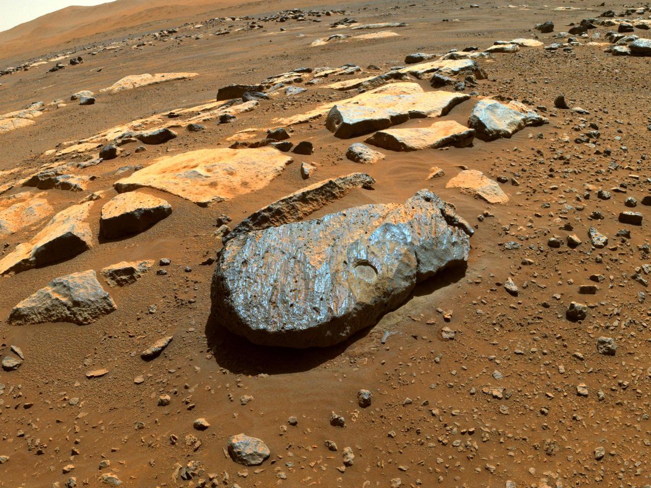 NASA's Perseverance rover took this image of the Martian rock nicknamed "Rochette" on Aug. 27, 2021, shortly after it abraded a circular patch known as "Bellegarde." The patch is about 0.39 inches (10 millimeters) deep and about 2 inches (5 centimeters) in diameter.  The image was taken by one of the rover's Hazard Avoidance Cameras on the 185th sol (Martian day) of the rover's mission and processed to enhance contrast.  A key objective for Perseverance's mission on Mars is astrobiology, including the search for signs of ancient microbial life. The rover will characterize the planet's geology and past climate, pave the way for human exploration of the Red Planet, and be the first mission to collect and cache Martian rock and regolith.  The Mars 2020 Perseverance mission is part of NASA's Moon to Mars exploration approach, which includes Artemis missions to the Moon that will help prepare for human exploration of the Red Planet.  Subsequent NASA missions, in cooperation with ESA (European Space Agency), would send spacecraft to Mars to collect these sealed samples from the surface and return them to Earth for in-depth analysis.  https://photojournal.jpl.nasa.gov/catalog/PIA24839