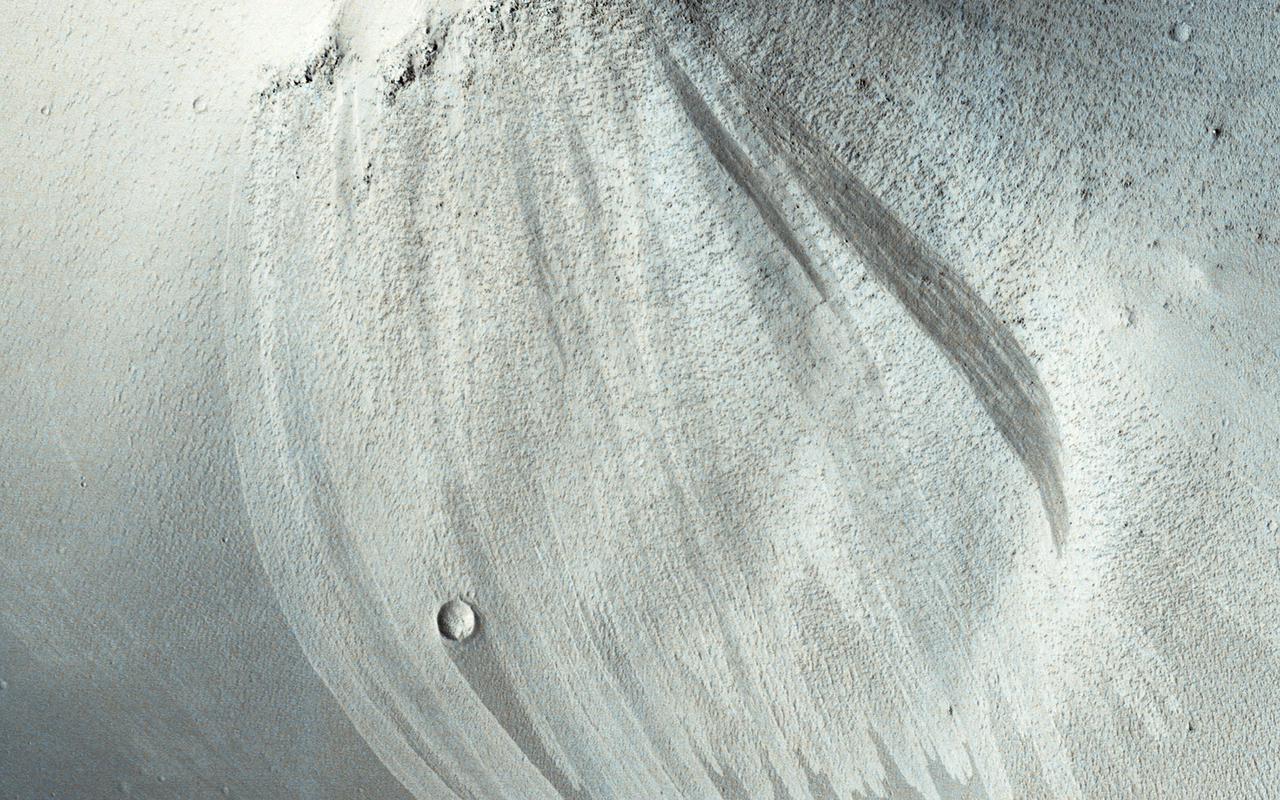 Slope streaks are common in the tropics of Mars. Once thought to be caused by flowing water, most scientists now believe that they are avalanches of dust. They are typically darker than their surroundings and often fan outwards downslope. This suggests that the dust sediment is sticky, so that the avalanche broadens as it flows downhill. Slope streaks are known to fade over time, but the slope streaks at this monitoring site in Arabia Terra go beyond that. Here, old slope streaks appear to be brighter than the surrounding terrain. A comparison between HiRISE images taken in 2008 and in 2019 shows very few changes in the dark and bright streaks. We can see three new dark streaks in our more recent image. These were the only changes spotted among the hundreds of streaks observed in the monitoring site, suggesting that new streak formation and fading take place on time scales of at least decades. https://photojournal.jpl.nasa.gov/catalog/PIA24912