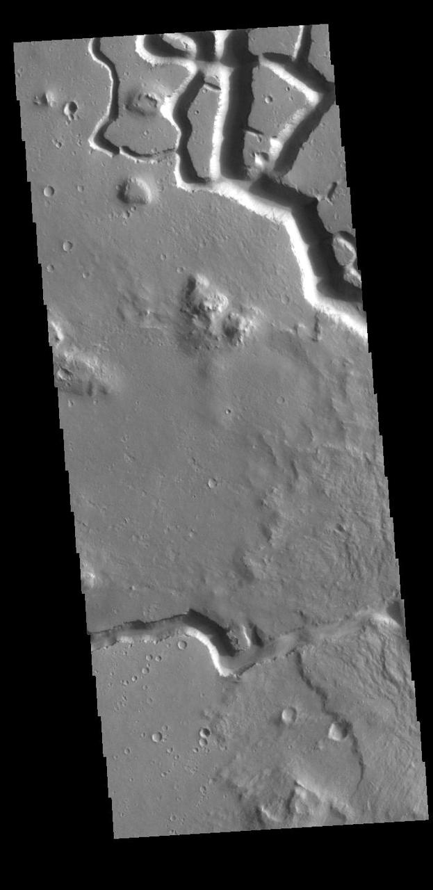 This VIS image shows part of Hephaestus Fossae. Hephaestus Fossae is a complex channel system in Utopia Planitia near Elysium Mons. It has been proposed that the channel formed by the release of melted subsurface ice during the impact event that created the crater just off the bottom right of the image – only the ejecta is seen in this image. The crater is fairly young, as there is only minimal modification of the crater floor. While it appears that the crater sits of top of the channel, the creation of the crater may have also created the channel. The impact event would have caused subsurface heating, melting any subsurface ice in the region which would have created surface flow to form the channel. Additionally, the nearby Elysium volcanic center created subsurface heating that may have played a part in creating both Hephaestus Fossae and Hebrus Valles to the north. The THEMIS VIS camera is capable of capturing color images of the Martian surface using five different color filters. In this mode of operation, the spatial resolution and coverage of the image must be reduced to accommodate the additional data volume produced from using multiple filters. To make a color image, three of the five filter images (each in grayscale) are selected. Each is contrast enhanced and then converted to a red, green, or blue intensity image. These three images are then combined to produce a full color, single image. Because the THEMIS color filters don't span the full range of colors seen by the human eye, a color THEMIS image does not represent true color. Also, because each single-filter image is contrast enhanced before inclusion in the three-color image, the apparent color variation of the scene is exaggerated. Nevertheless, the color variation that does appear is representative of some change in color, however subtle, in the actual scene. Note that the long edges of THEMIS color images typically contain color artifacts that do not represent surface variation. Orbit Number: 86796 Latitude: 17.9392 Longitude: 125.437 Instrument: VIS Captured: 2021-07-09 02:13 https://photojournal.jpl.nasa.gov/catalog/PIA24995
