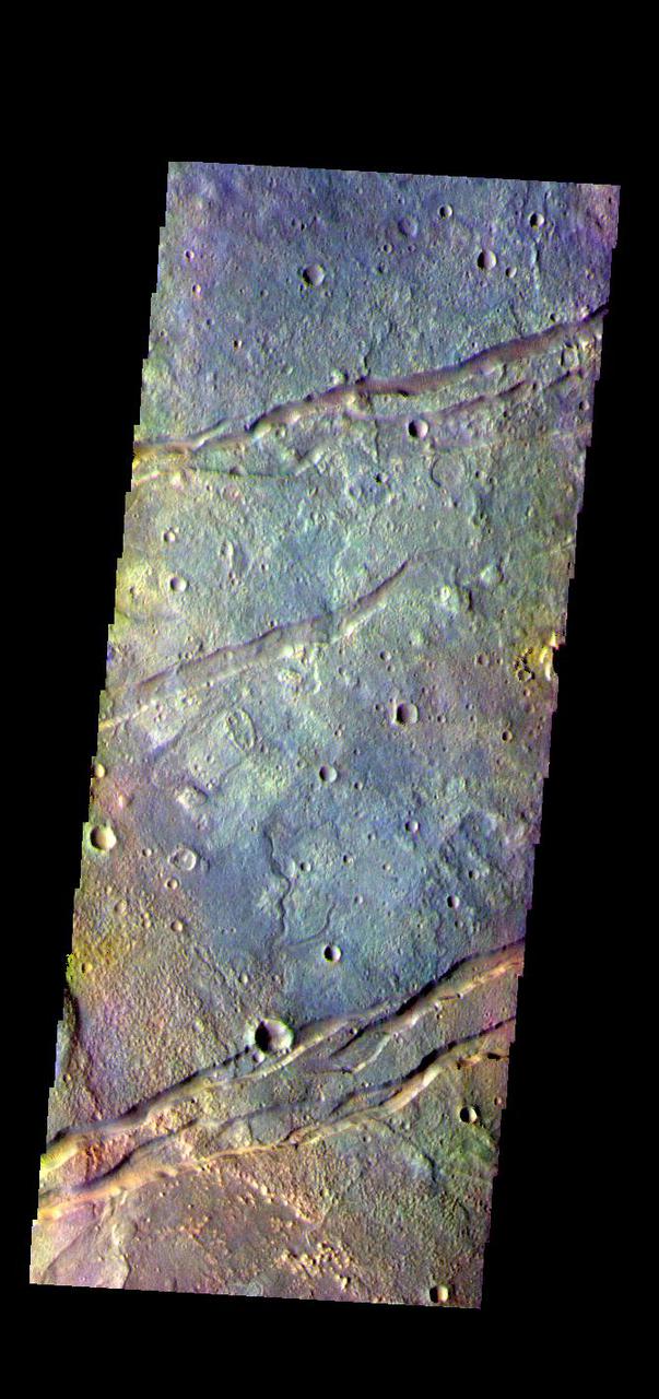 The THEMIS VIS camera contains 5 filters. The data from different filters can be combined in multiple ways to create a false color image. These false color images may reveal subtle variations of the surface not easily identified in a single band image. Today's false color image shows part of Sirenum Fossae. The linear depressions in this VIS image are tectonic graben. Graben are formed by extension of the crust and faulting. When large amounts of pressure or tension are applied to rocks on timescales that are fast enough that the rock cannot respond by deforming, the rock breaks along faults. In the case of a graben, two parallel faults are formed by extension of the crust and the rock in between the faults drops downward into the space created by the extension. Several graben are visible in this THEMIS VIS image, trending from north-northeast to south-southwest. Because the faults defining the graben are formed parallel to the direction of the applied stress, we know that extensional forces were pulling the crust apart in the west-northwest/east-southeast direction. The Sirenum Fossae graben are 2735km (1700 miles) long.  The THEMIS VIS camera is capable of capturing color images of the Martian surface using five different color filters. In this mode of operation, the spatial resolution and coverage of the image must be reduced to accommodate the additional data volume produced from using multiple filters. To make a color image, three of the five filter images (each in grayscale) are selected. Each is contrast enhanced and then converted to a red, green, or blue intensity image. These three images are then combined to produce a full color, single image. Because the THEMIS color filters don't span the full range of colors seen by the human eye, a color THEMIS image does not represent true color. Also, because each single-filter image is contrast enhanced before inclusion in the three-color image, the apparent color variation of the scene is exaggerated. Nevertheless, the color variation that does appear is representative of some change in color, however subtle, in the actual scene. Note that the long edges of THEMIS color images typically contain color artifacts that do not represent surface variation.  Orbit Number: 83755 Latitude: -32.1324 Longitude: 205.871 Instrument: VIS Captured: 2020-10-31 16:02  https://photojournal.jpl.nasa.gov/catalog/PIA25001