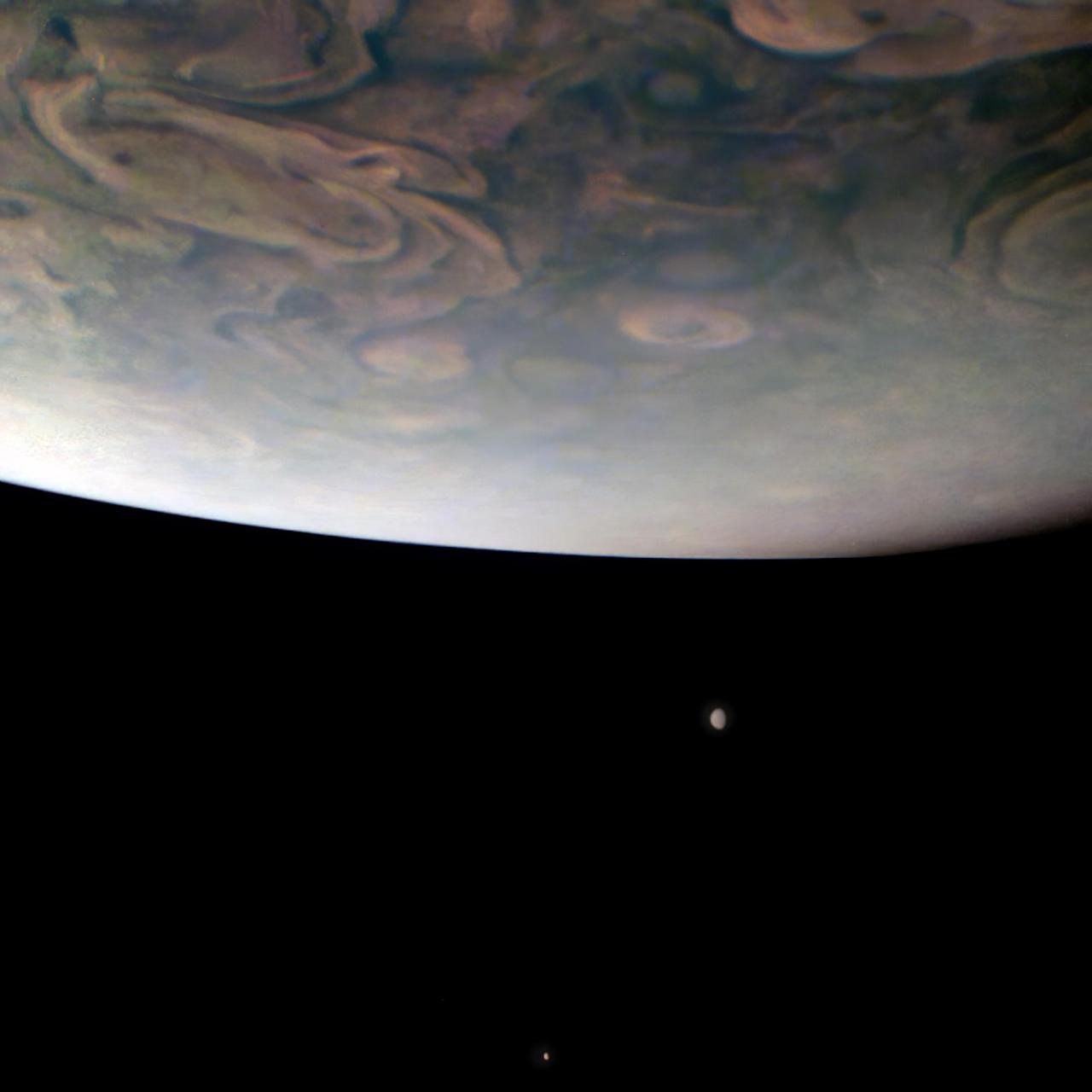 On Nov. 29, 2021, NASA's Juno mission completed its 38th close flyby of Jupiter. As the spacecraft sped low over the giant planet's cloud tops, its JunoCam instrument captured this look at two of Jupiter's largest moons.  In the foreground, hurricane-like spiral wind patterns called vortices can be seen spinning in the planet's north polar region. These powerful storms can be over 30 miles (50 kilometers) in height and hundreds of miles across.  Below Jupiter's curving horizon, two Jovian moons make an appearance: Callisto (below) and Io (above).  Juno will make close flybys of Io in December 2023 and February 2024, the first such close encounters with this intriguing moon in over two decades. Io is the most volcanic body in our solar system, and its eruptions leave a trail of material behind that both fills Jupiter's magnetosphere and creates a torus of gas and dust around Jupiter. During the flybys, Juno will study Io's volcanoes and geology, search for signs of a magma ocean, and investigate how Io interacts with Jupiter's giant magnetosphere.  Citizen scientist Gerald Eichstädt used raw JunoCam data to make the original version of this image, and then another citizen scientist, Thomas Thomopoulos, further processed it, zooming in and making color enhancements.  In this view, north is down. At the time the image was taken, Juno was about 8,700 miles (14,000 kilometers) above Jupiter's cloud tops, at a latitude of about 69 degrees, traveling at a speed of about 123,000 mph (198,000 kilometers per hour) relative to the planet.  https://photojournal.jpl.nasa.gov/catalog/PIA25019