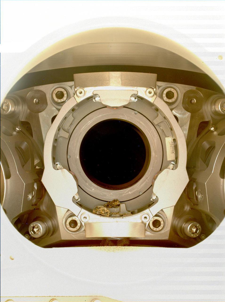 This image of pebble-sized debris in the bit carousel on NASA's Perseverance Mars rover was acquired on Jan. 7, 2022, by the WATSON camera. The image was taken to assist the Perseverance team in diagnosing an anomaly that occurred during a rock sampling on Dec. 29, 2021.  A subsystem of the SHERLOC (Scanning Habitable Environments with Raman & Luminescence for Organics & Chemicals) instrument, WATSON can document the structure and texture within a drilled or abraded target, and its data can be used to derive depth measurements.  NASA's Jet Propulsion Laboratory built and manages operations of Perseverance and Ingenuity for the agency. Caltech in Pasadena, California, manages JPL for NASA. WATSON was built by Malin Space Science Systems (MSSS) in San Diego and is operated jointly by MSSS and JPL.  A key objective for Perseverance's mission on Mars is astrobiology, including the search for signs of ancient microbial life. The rover will characterize the planet's geology and past climate, pave the way for human exploration of the Red Planet, and be the first mission to collect and cache Martian rock and regolith (broken rock and dust).  Subsequent NASA missions, in cooperation with ESA (European Space Agency), would send spacecraft to Mars to collect these sealed samples from the surface and return them to Earth for in-depth analysis.  The Mars 2020 Perseverance mission is part of NASA's Moon to Mars exploration approach, which includes Artemis missions to the Moon that will help prepare for human exploration of the Red Planet.  https://photojournal.jpl.nasa.gov/catalog/PIA25066