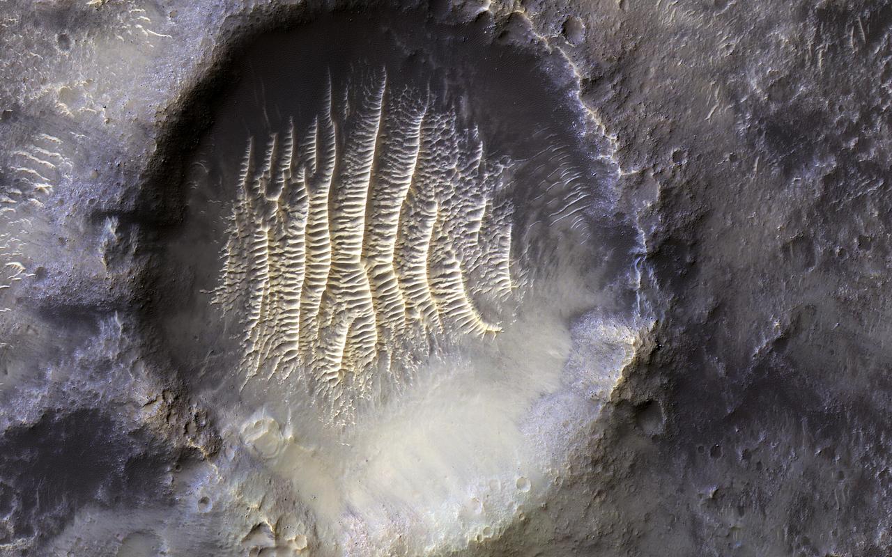 The crater in the center of this HiRISE image defines where zero longitude is on Mars, like the Greenwich Observatory does for the Earth. Originally, the larger crater that this crater sits within, called Airy Crater, defined zero longitude for the Red Planet. But as higher resolution images became available, a smaller feature was needed. This crater, called Airy-0 (zero), was selected because it would require no adjustment of existing maps. These days, longitude on Mars is measured even more precisely using radio tracking of landers such as InSight, but everything is still defined to keep zero longitude centered on this crater. https://photojournal.jpl.nasa.gov/catalog/PIA25090