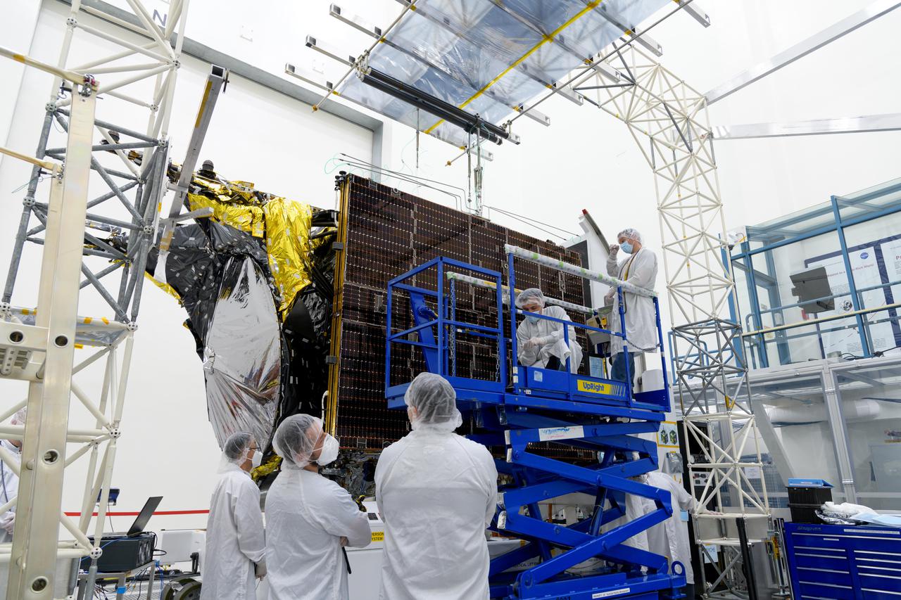 Engineers at NASA's Jet Propulsion Laboratory in Southern California examine one of Psyche's stowed solar arrays prior to a deployment test in the Lab's High Bay 2 clean room in late February 2022.  The twin arrays are together about 800 square feet (75 square meters) – the largest ever deployed at JPL. Part of a solar electric propulsion system provided by Maxar Technologies, they will power the spacecraft on its 1.5 billion-mile (2.4 billion-kilometer) journey to the large, metal-rich asteroid Psyche.  Only the three center panels on each five-panel, cross-shaped array can be deployed at JPL due to the limitations of the gravity-offload fixture and the opposing direction of rotation of the cross panels. Deployment of the two cross panels was previously performed at Maxar with different equipment. After further spacecraft testing is completed at JPL, the arrays will be removed and returned to Maxar in order to repeat the cross-panel deployments, make any final repairs to the solar cells, and test overall performance. The arrays then get shipped from Maxar to NASA's Kennedy Space Center in Florida, where they will be reintegrated onto the spacecraft in preparation for launch in August 2022.  About an hour after launch, Psyche will deploy the arrays sequentially, first unfolding the three lengthwise center panels, then the two cross panels on one wing before repeating the process with the other wing. Each array takes about 7 ½ minutes to unfurl and latch into place.  Each array is 37.1 feet (11.3 meters) long and 24 feet (7.3 meters) wide when fully deployed. With arrays deployed on either side of the chassis, the spacecraft is about the size of a singles tennis court: 81 feet long (24.7 meters) and 24 feet (7.3 meters) wide.  https://photojournal.jpl.nasa.gov/catalog/PIA25132