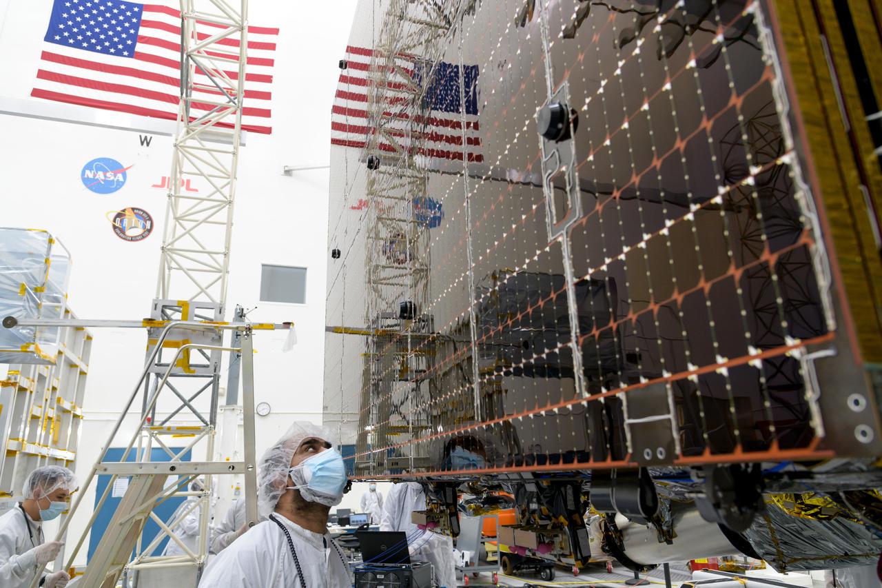 An engineer at NASA's Jet Propulsion Laboratory in Southern California examines a panel on Psyche's stowed solar arrays prior to a deployment test in the Lab's High Bay 2 clean room in February 2022.  The twin arrays are together about 800 square feet (75 square meters) – the largest ever deployed at JPL. Part of a solar electric propulsion system provided by Maxar Technologies, they will power the spacecraft on its 1.5 billion-mile (2.4 billion-kilometer) journey to the large, metal-rich asteroid Psyche.  Only the three center panels on each five-panel, cross-shaped array can be deployed at JPL due to the limitations of the gravity-offload fixture and the opposing direction of rotation of the cross panels. Deployment of the two cross panels was previously performed at Maxar with different equipment. After further spacecraft testing is completed at JPL, the arrays will be removed and returned to Maxar in order to repeat the cross-panel deployments, make any final repairs to the solar cells, and test overall performance. The arrays then get shipped from Maxar to NASA's Kennedy Space Center in Florida, where they will be reintegrated onto the spacecraft in preparation for launch in August 2022.  About an hour after launch, Psyche will deploy the arrays sequentially, first unfolding the three lengthwise center panels, then the two cross panels on one wing before repeating the process with the other wing. Each array takes about 7 ½ minutes to unfurl and latch into place.  Each array is 37.1 feet (11.3 meters) long and 24 feet (7.3 meters) wide when fully deployed. With arrays deployed on either side of the chassis, the spacecraft is about the size of a singles tennis court: 81 feet long (24.7 meters) and 24 feet (7.3 meters) wide.  https://photojournal.jpl.nasa.gov/catalog/PIA25133