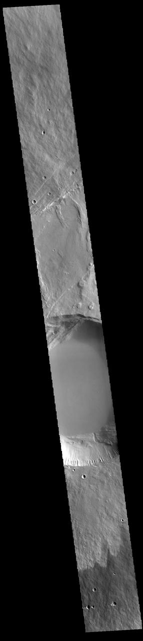This VIS image shows a cross section of Pavonis Mons, including the central part of the smaller summit caldera (circular depression). On the top side of the caldera is a complex region of fault related collapse of the wall of the caldera. Several intersecting faults are visible there. The faults would have formed areas of weakness in the caldera wall, precipitating into gravity driven down slope movement of materials. This caldera is approximately 5km (3 miles) deep, much deeper that the larger caldera that surrounds the northern and eastern sides of the small caldera. Pavonis Mons, like the other large volcanoes in the region, is a shield volcano. Shield volcanoes are formed by lava flows originating near or at the summit, building up layers upon layers of lava. In shield volcanoes summit calderas are typically formed where the surface collapses into the void formed by an emptied magma chamber.  Pavonis Mons is one of the three aligned Tharsis Volcanoes. In order from north to south are Ascreaus Mons, Pavonis Mons and Arsia Mons. The three aligned volcanoes are located along a topographic rise in the Tharsis region. Along this trend there are increased tectonic features and additional lava flows that arose from the flanks of the volcanoes rather than the summit. Pavonis Mons is the smallest of the three volcanoes, rising 14 km (8 miles) above the mean Mars surface level with a width of 375 km (233 miles). Like most shield volcanoes the surface has a low profile. In the case of Pavonis Mons the average slope is only 4 degrees.  Orbit Number: 88177 Latitude: 0.900987 Longitude: 247.141 Instrument: VIS Captured: 2021-10-30 19:09  https://photojournal.jpl.nasa.gov/catalog/PIA25157