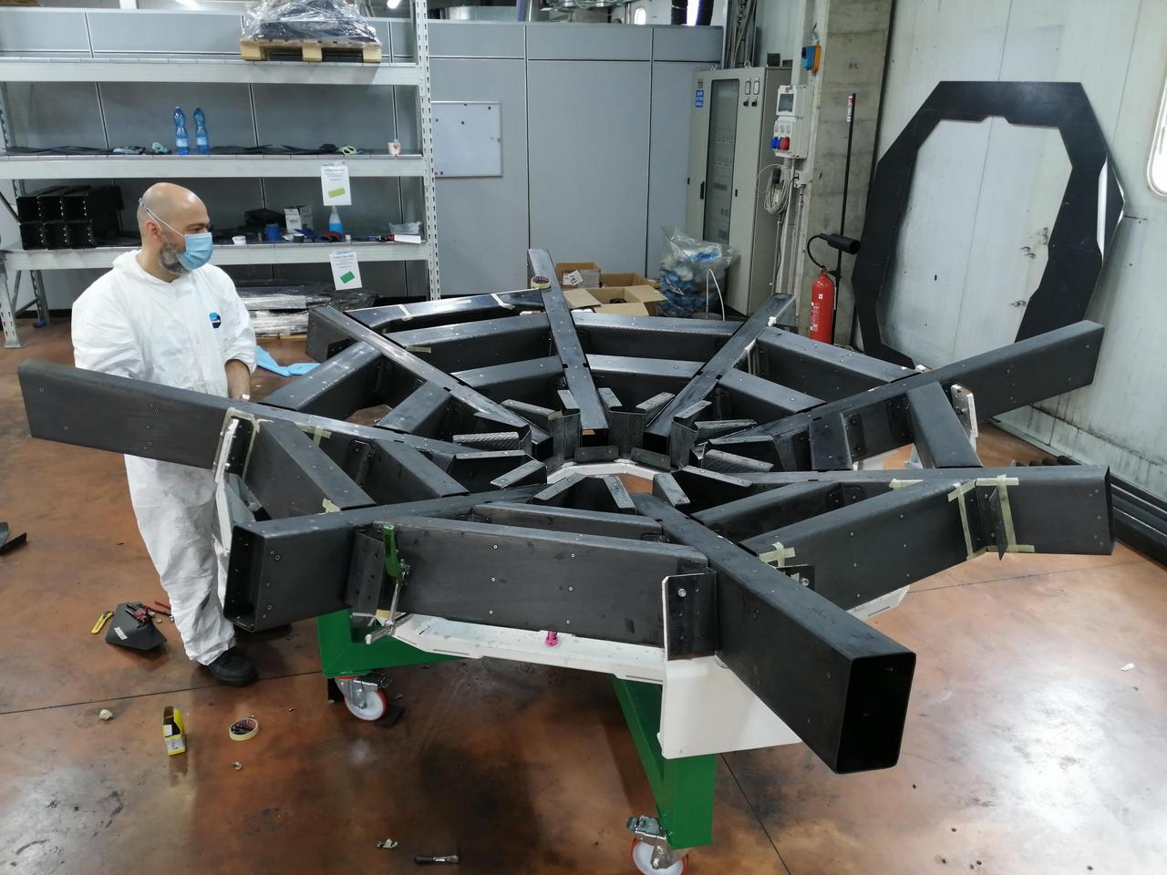 Known as the cradle, the structure that supports the primary mirror on NASA's Astrophysics Stratospheric Telescope for High Spectral Resolution Observations at Submillimeter-wavelengths mission, or ASTHROS, keeps the mirror panels aligned. Made from carbon fiber, it and must be both lightweight and extremely rigid.  NASA contracted Media Lario, an optics company in Bosisio Parini, Italy, to design and produce ASTHROS' full telescope unit, including the primary mirror, a secondary mirror, and supporting structure (called the cradle). The cradle is shown here at Media Lario.  The mission's main science goal is to study stellar feedback, the process by which living stars disperse and reshape clouds of gas and dust that may eventually form new stars. Feedback regulates star formation in many galaxies, and too much can halt star formation entirely. ASTHROS will look at several star-forming regions in our galaxy where feedback takes place, and at distant galaxies containing millions of stars to see how feedback plays out at large scales and in different environments.  https://photojournal.jpl.nasa.gov/catalog/PIA25169