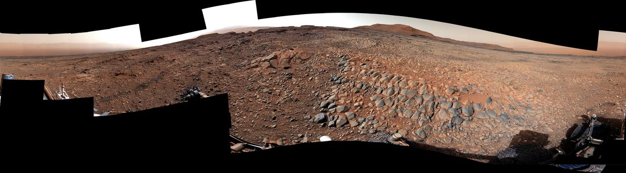 NASA's Curiosity Mars rover used its Mast Camera, or Mastcam, to take this 360-degree panorama on March 23, 2022, the 3,423th Martian day, or sol, of the mission. The team has informally described the wind-sharpened rocks seen here as "gator-back" rocks because of their scaly appearance.  Wind-sharpened rocks like these are called ventifacts, and are responsible for chewing up Curiosity's wheels earlier in the mission. Since then, rover engineers have found ways to slow wheel wear, including a traction control algorithm. They also plan rover routes that avoid driving over such rocks, including these latest ventifacts, which are made of sandstone – the hardest type of rock Curiosity has encountered on Mars.  These rocks form the surface of the "Greenheugh Pediment," a broad, sloping plain in the foothills of Mount Sharp. The floor of Gale Crater is visible along the edges of the mosaic. When Curiosity's team saw the gator-back rocks, they ultimately decided to turn the rover around and take an alternative path to continue climbing Mount Sharp, a 3.4-mile-tall (5.5-kilometer-tall) mountain that Curiosity has been ascending since 2014. As it climbs, Curiosity is able to study different sedimentary layers shaped by water billions of years ago. These layers help scientists understand whether microscopic life could have survived in the ancient Martian environment.  https://photojournal.jpl.nasa.gov/catalog/PIA25176