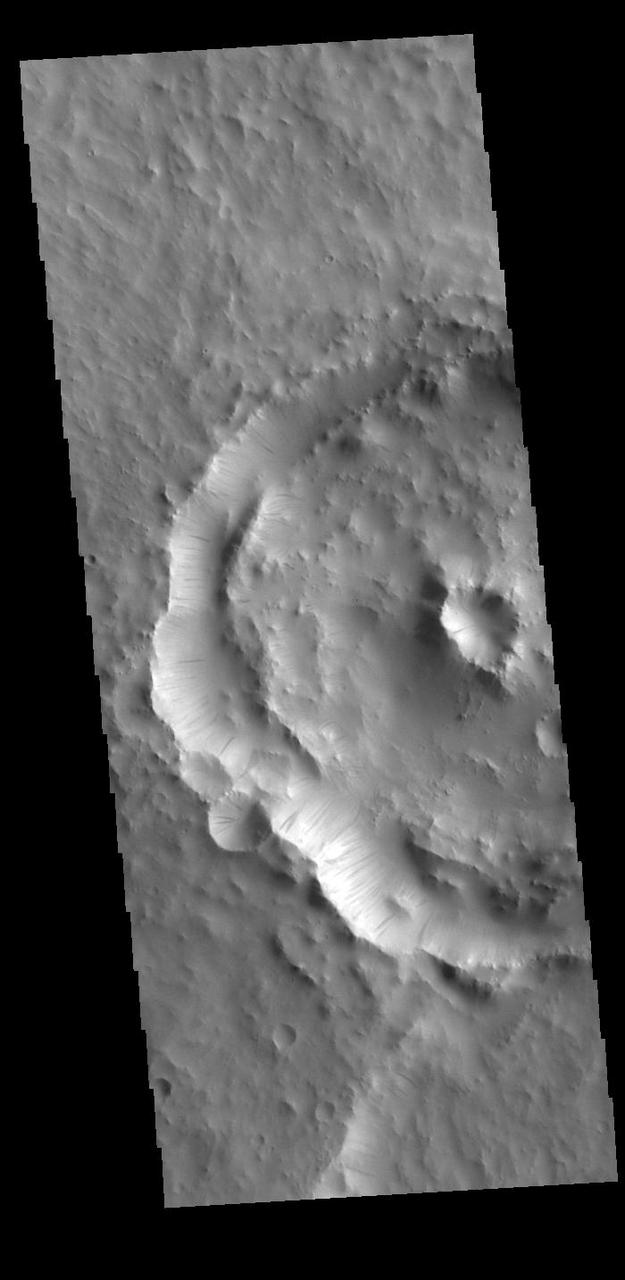 Dark streaks mark the inner rim of this unnamed crater in Terra Sabaea. There are several suggested mechanisms to form these features. Two of the mechanisms are that the dusty surface has been altered to reveal darker rock beneath from motion of downward moving dust avalanches, or the surface is darkening by fluid or other surface staining.  Orbit Number: 87336 Latitude: 14.6769 Longitude: 27.535 Instrument: VIS Captured: 2021-08-22 13:18  https://photojournal.jpl.nasa.gov/catalog/PIA25210