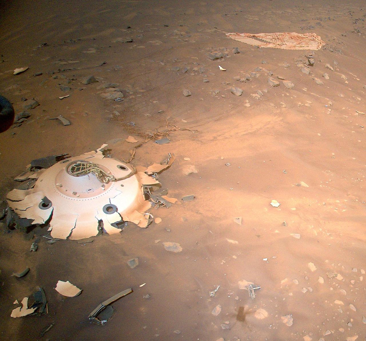 This image of Perseverance's backshell and parachute was collected from an altitude of 26 feet (8 meters) by the NASA's Ingenuity Mars Helicopter during its 26th flight on Mars on April 19, 2022.  The parachute and cone-shaped backshell protected the rover during its fiery descent toward the Martian surface on Feb. 18, 2021. Engineers working on the Mars Sample Return program requested images be taken of the components from an aerial perspective because they may provide insight into the components' performance during the rover's entry, descent, and landing.  https://photojournal.jpl.nasa.gov/catalog/PIA25217