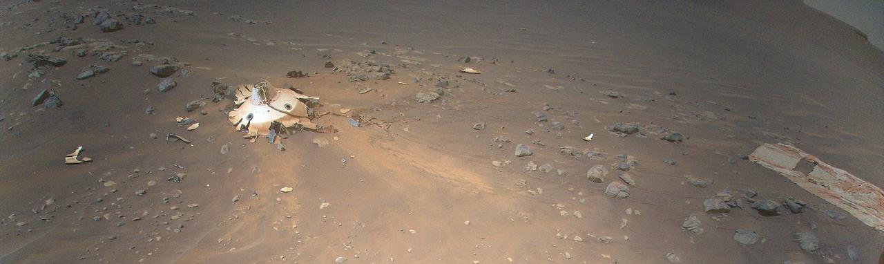 This image of Perseverance's backshell (left of center), supersonic parachute (far right), was collected from an altitude of 26 feet (8 meters) by NASA's Ingenuity Mars Helicopter during its 26th flight on Mars on April 19, 2022.  During the Feb. 18, 2021, landing of Perseverance, the parachute and backshell were jettisoned at about 1.3 miles (2.1 km) altitude. The parachute and backshell continued to descend and impacted the ground at approximately 78 mph (126 kph). Engineers working on the Mars Sample Return program requested images be taken from an aerial perspective of the components because they may provide insight into the components' performance during the rover's entry, descent, and landing.  The image has been cropped and processed from the original version.  https://photojournal.jpl.nasa.gov/catalog/PIA25218