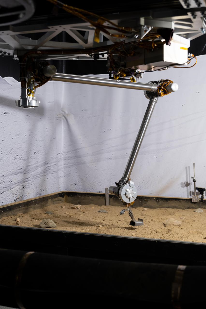 The 3D-printed titanium scoop of the Cold Operable Lunar Deployable Arm (COLDArm) robotic arm system is poised above a test bed filled with material to simulate lunar regolith (broken rocks and dust) at NASA's Jet Propulsion Laboratory in Southern California. COLDArm can function in temperatures as cold as minus 280 degrees Fahrenheit (minus 173 degrees Celsius).  COLDArm is designed to go on a Moon lander and operate during lunar night, a period that lasts about 14 Earth days. Frigid temperatures during lunar night would stymie current spacecraft, which must rely on energy-consuming heaters to stay warm.  To operate in the cold, the 6-foot-6-inch (2-meter) arm combines several key new technologies: gears made of bulk metallic glass that require no lubrication or heating, cold motor controllers that don't need to be kept warm in an electronics box near the core of the spacecraft, and a cryogenic six-axis force torque sensor that lets the arm "feel" what it's doing and make adjustments.  A variety of attachments and small instruments could go on the end of the arm, including the scoop, which could be used for collecting samples from a planet's surface. Like the arm on NASA's InSight Mars lander, COLDArm could deploy science instruments to the surface.  https://photojournal.jpl.nasa.gov/catalog/PIA25317