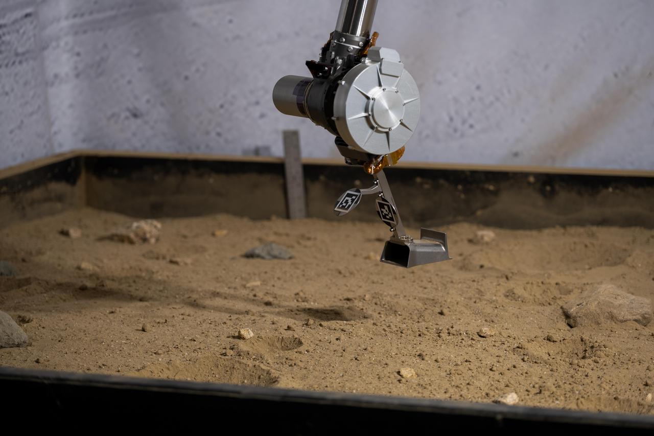 The 3D-printed titanium scoop of the Cold Operable Lunar Deployable Arm (COLDArm) robotic arm system is poised above a test bed filled with material to simulate lunar regolith (broken rocks and dust) at NASA's Jet Propulsion Laboratory in Southern California. COLDArm can function in temperatures as cold as minus 280 degrees Fahrenheit (minus 173 degrees Celsius).  COLDArm is designed to go on a Moon lander and operate during lunar night, a period that lasts about 14 Earth days. Frigid temperatures during lunar night would stymie current spacecraft, which must rely on energy-consuming heaters to stay warm.  To operate in the cold, the 6-foot-6-inch (2-meter) arm combines several key new technologies: gears made of bulk metallic glass that require no lubrication or heating, cold motor controllers that don't need to be kept warm in an electronics box near the core of the spacecraft, and a cryogenic six-axis force torque sensor that lets the arm "feel" what it's doing and make adjustments.  A variety of attachments and small instruments could go on the end of the arm, including the scoop, which could be used for collecting samples from a planet's surface. Like the arm on NASA's InSight Mars lander, COLDArm could deploy science instruments to the surface.  https://photojournal.jpl.nasa.gov/catalog/PIA25318