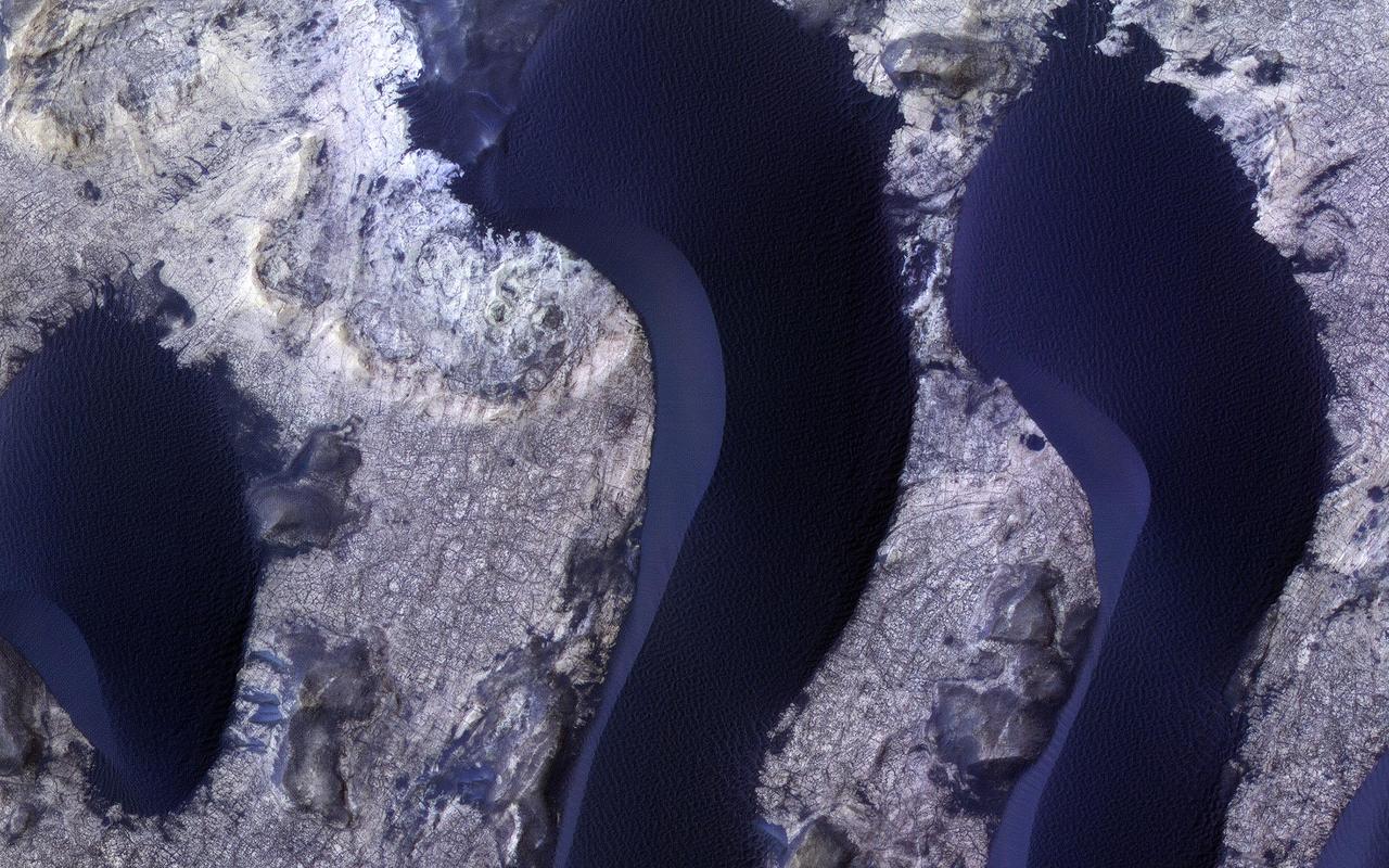 HiRISE monitors dune fields across Mars to track how they are changing. The mobile sand also cleans dust off of the bedrock in inter-dune areas, providing good views of the bedrock structures and colors. Here we see subtle color differences between layers, and a dense network of fractures. The dunes, in contrast, are uniformly dark and relatively blue in enhanced color (really grey but less red than the bedrock, so they appear blue here). https://photojournal.jpl.nasa.gov/catalog/PIA25351