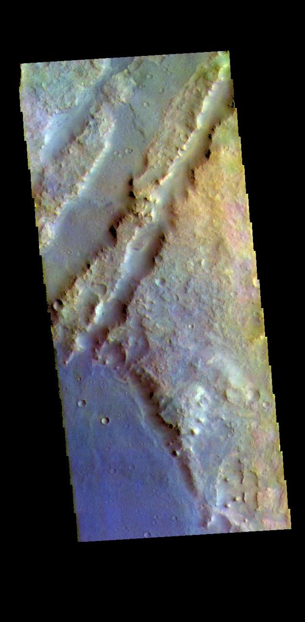 The THEMIS VIS camera contains 5 filters. The data from different filters can be combined in multiple ways to create a false color image. These false color images may reveal subtle variations of the surface not easily identified in a single band image. The linear depressions in today's false color image are part of Nili Fossae. Nili Fossae is a collection of curved faults and down-dropped blocks of crust between the faults. The "fossae," or graben, lie northeast of the large volcano Syrtis Major and northwest of the ancient impact basin Isidis Planitia. The troughs, which can be almost 500 meters (1,600 feet) deep , make concentric curves that follow the outline of Isidis Planitia. The graben likely formed as the crust sagged under the weight of lava flows filling the Isidis Planitia impact basin.  The THEMIS VIS camera is capable of capturing color images of the Martian surface using five different color filters. In this mode of operation, the spatial resolution and coverage of the image must be reduced to accommodate the additional data volume produced from using multiple filters. To make a color image, three of the five filter images (each in grayscale) are selected. Each is contrast enhanced and then converted to a red, green, or blue intensity image. These three images are then combined to produce a full color, single image. Because the THEMIS color filters don't span the full range of colors seen by the human eye, a color THEMIS image does not represent true color. Also, because each single-filter image is contrast enhanced before inclusion in the three-color image, the apparent color variation of the scene is exaggerated. Nevertheless, the color variation that does appear is representative of some change in color, however subtle, in the actual scene. Note that the long edges of THEMIS color images typically contain color artifacts that do not represent surface variation.  Orbit Number: 88158 Latitude: 20.507 Longitude: 72.6076 Instrument: VIS Captured: 2021-10-29 05:43  https://photojournal.jpl.nasa.gov/catalog/PIA25388