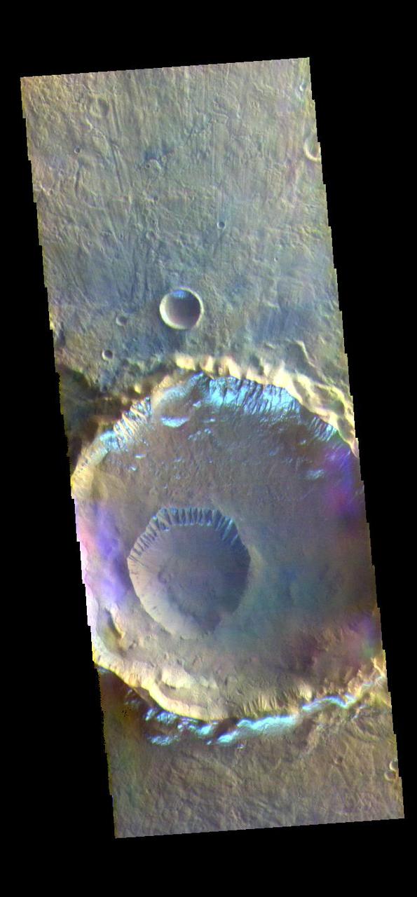 The THEMIS VIS camera contains 5 filters. The data from different filters can be combined in multiple ways to create a false color image. These false color images may reveal subtle variations of the surface not easily identified in a single band image. Today's false color image shows several craters in Eridania Planitia. The small crater inside the larger crater is Gasa Crater. The larger crater is unnamed. The bright silver-blue region on the inner and outer crater rim is morning frost. Collected during the winter, south facing slopes stay in shadow and retain frost longer than the rest of the rim already in sunlight. Frosts are only identifiable in multi filter images. The THEMIS VIS camera is capable of capturing color images of the Martian surface using five different color filters. In this mode of operation, the spatial resolution and coverage of the image must be reduced to accommodate the additional data volume produced from using multiple filters. To make a color image, three of the five filter images (each in grayscale) are selected. Each is contrast enhanced and then converted to a red, green, or blue intensity image. These three images are then combined to produce a full color, single image. Because the THEMIS color filters don't span the full range of colors seen by the human eye, a color THEMIS image does not represent true color. Also, because each single-filter image is contrast enhanced before inclusion in the three-color image, the apparent color variation of the scene is exaggerated. Nevertheless, the color variation that does appear is representative of some change in color, however subtle, in the actual scene. Note that the long edges of THEMIS color images typically contain color artifacts that do not represent surface variation. Orbit Number: 88618 Latitude: -35.5932 Longitude: 129.422 Instrument: VIS Captured: 2021-12-06 02:28 https://photojournal.jpl.nasa.gov/catalog/PIA25389