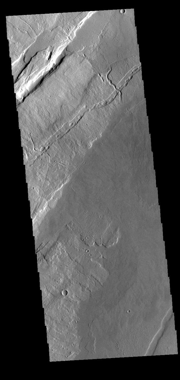 The linear features in this VIS image are called Oti Fossae. Oti Fossae is located on the eastern flank of Arsia Mons and aligns with the regional northeast/southwest trend of the major Tharsis volcanoes.  Graben are formed by extension of the crust and faulting. When large amounts of pressure or tension are applied to rocks on timescales that are fast enough that the rock cannot respond by deforming, the rock breaks along faults. In the case of a graben, two parallel faults are formed by extension of the crust and the rock in between the faults drops downward into the space created by the extension. The crustal deformation in this region was from the inflation of the surface by the rise of magma that created the Tharsis volcanoes.  Arsia Mons is the southernmost and youngest of the three large, aligned Tharsis volcanoes [Arsia Mons, Pavonis Mons and Ascreaus Mons, from south to north]. This alignment may indicate a large fracture/vent system was responsible for the eruptions that formed all three volcanoes. Arsia Mons is 270 miles (450km) in diameter, almost 12 miles (20km) high, and the summit caldera is 72 miles (120km) wide. For comparison, the largest volcano on Earth is Mauna Loa. From its base on the sea floor, Mauna Loa measures only 6.3 miles high and 75 miles in diameter.  Orbit Number: 89712 Latitude: -8.73951 Longitude: 243.785 Instrument: VIS Captured: 2022-03-06 04:33  https://photojournal.jpl.nasa.gov/catalog/PIA25392
