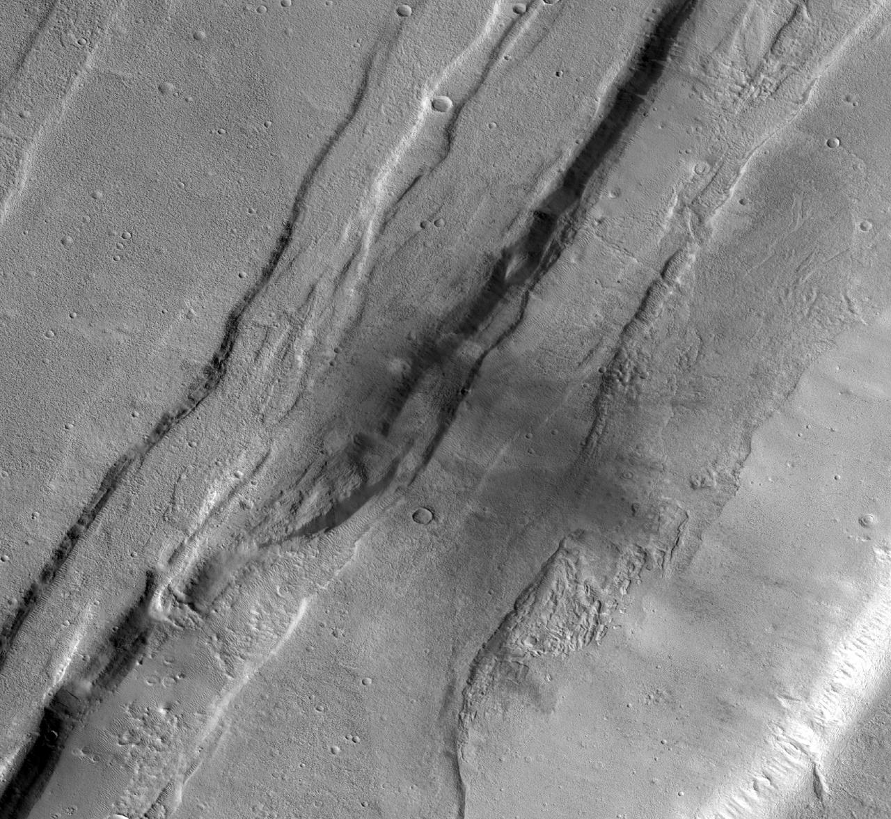 This meteoroid impact crater on Mars was captured using the black-and-white Context Camera aboard NASA's Mars Reconnaissance Orbiter (MRO). The Context Camera took this image showing the impact, which occurred Sept. 18, 2021, in a region called Tempe Terra. The meteoroid struck the side of a graben – a depression created by faults. The impact crater left behind is roughly 427 feet (130 meters) across. https://photojournal.jpl.nasa.gov/catalog/PIA25587