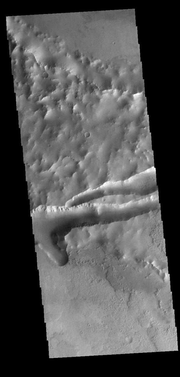 This VIS image shows part of Mangala Fossae. Fossae are long linear depressions called a graben and were formed by extension of the crust and faulting. When large amounts of pressure or tension are applied to rocks on timescales that are fast enough that the rock cannot respond by deforming, the rock breaks along faults. In the case of a graben, two parallel faults are formed by extension of the crust and the rock in between the faults drops downward into the space created by the extension. Mangala Fossae is 828 km long (514 miles). Orbit Number: 91672 Latitude: -15.2701 Longitude: 219.213 Instrument: VIS Captured: 2022-08-14 13:49 https://photojournal.jpl.nasa.gov/catalog/PIA25619