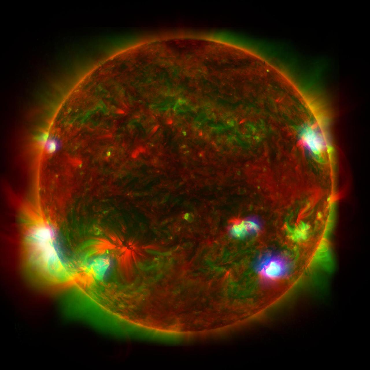 This composite image of the Sun includes high-energy X-ray data from NASA's Nuclear Spectroscopic Telescope Array (NuSTAR) shown in blue; lower energy X-ray data from the X-ray Telescope (XRT) on the Japanese Aerospace Exploration Agency's Hinode mission shown in green; and ultraviolet light detected by the Atmospheric Imaging Assembly (AIA) on NASA's Solar Dynamics Observatory (SDO) shown in red.  NuSTAR's relatively small field of view means it can't see the entire Sun from its position in Earth orbit, so Figure A is a composite of 25 images, which were taken by the observatory in June 2022. NuSTAR sees high-energy X-rays that appear at only a few locations, where the hottest material is present in the Sun's atmopshere. By contrast, Hinode's XRT and SDO's AIA detect detect wavelengths emitted across the entire face of the Sun. The hotspots observed by NuSTAR might be caused by collections of nanoflares, or small outbursts of heat, light, and particles from the Sun's surface that subsequently heat the atmosphere. Individual nanoflares are too faint to directly observe amid the Sun's blazing light.  https://photojournal.jpl.nasa.gov/catalog/PIA25628