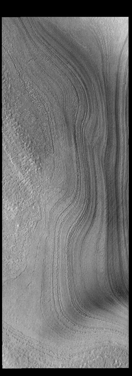This VIS image shows layering in the south polar cap. The layers are formed over thousands of years of seasonal change, reflecting ice and dust surface deposition. Where the layers appear close to each other are steep trough sides. The steeper the slope, the closer the layers. This image was collected during summer at the south polar cap.  Orbit Number: 91750 Latitude: -85.7516 Longitude: 177.751 Instrument: VIS Captured: 2022-08-20 23:34  https://photojournal.jpl.nasa.gov/catalog/PIA25633