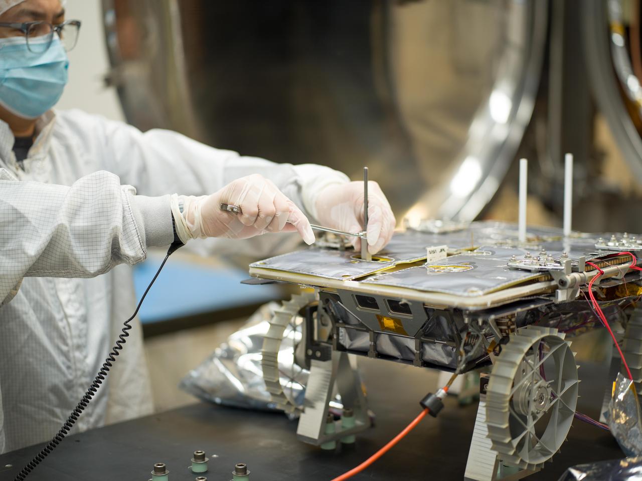 An engineer prepares a small rover – part of NASA's CADRE (Cooperative Autonomous Distributed Robotic Exploration) technology demonstration that's headed to the Moon – for testing in a thermal vacuum chamber at the agency's Jet Propulsion Laboratory in Southern California in October 2023.  Slated to arrive at the Moon in 2024 as part of NASA's CLPS (Commercial Lunar Payload Services) initiative, CADRE is designed to demonstrate that multiple robots can cooperate and explore together autonomously – without direct input from human mission controllers.  A trio of the miniature solar-powered rovers, each about the size of a carry-on suitcase, will explore the Moon as a team, communicating via radio with each other and a base station aboard a lunar lander. By taking simultaneous measurements from multiple locations, CADRE will also demonstrate how multirobot missions can record data impossible for a single robot to achieve – a tantalizing prospect for future missions.  The rover being tested is the first flight model to be completed. Thermal vacuum testing simulates the harsh environment the rovers will face on the journey to the Moon and on the lunar surface: All the air is pumped out of the chamber and the temperature is cycled to high and low extremes.  https://photojournal.jpl.nasa.gov/catalog/PIA25669