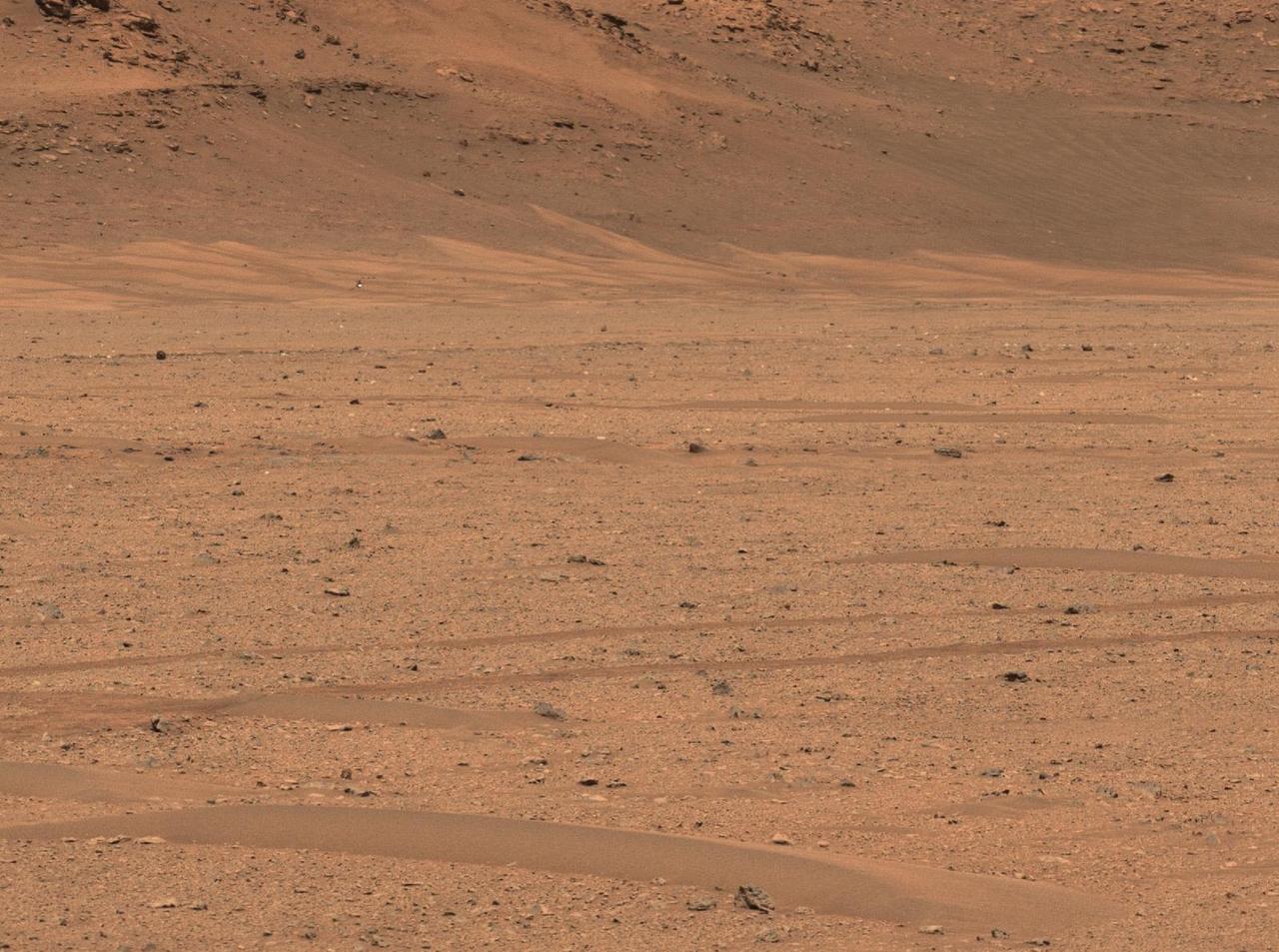 NASA's Perseverance Mars rover captured the agency's Ingenuity Mars Helicopter near the base of Jezero Crater's river delta in this image taken Dec. 18, 2022, the 650th day, or sol, of the mission. At the time the picture was taken, the helicopter was about 1,115 feet (340 meters) northeast of the rover.  A key objective for Perseverance's mission on Mars is astrobiology, including the search for signs of ancient microbial life. The rover will characterize the planet's geology and past climate, pave the way for human exploration of the Red Planet, and be the first mission to collect and cache Martian rock and regolith (broken rock and dust).  Subsequent NASA missions, in cooperation with ESA (European Space Agency), would send spacecraft to Mars to collect these sealed samples from the surface and return them to Earth for in-depth analysis.  The Mars 2020 Perseverance mission is part of NASA's Moon to Mars exploration approach, which includes Artemis missions to the Moon that will help prepare for human exploration of the Red Planet.  https://photojournal.jpl.nasa.gov/catalog/PIA25683