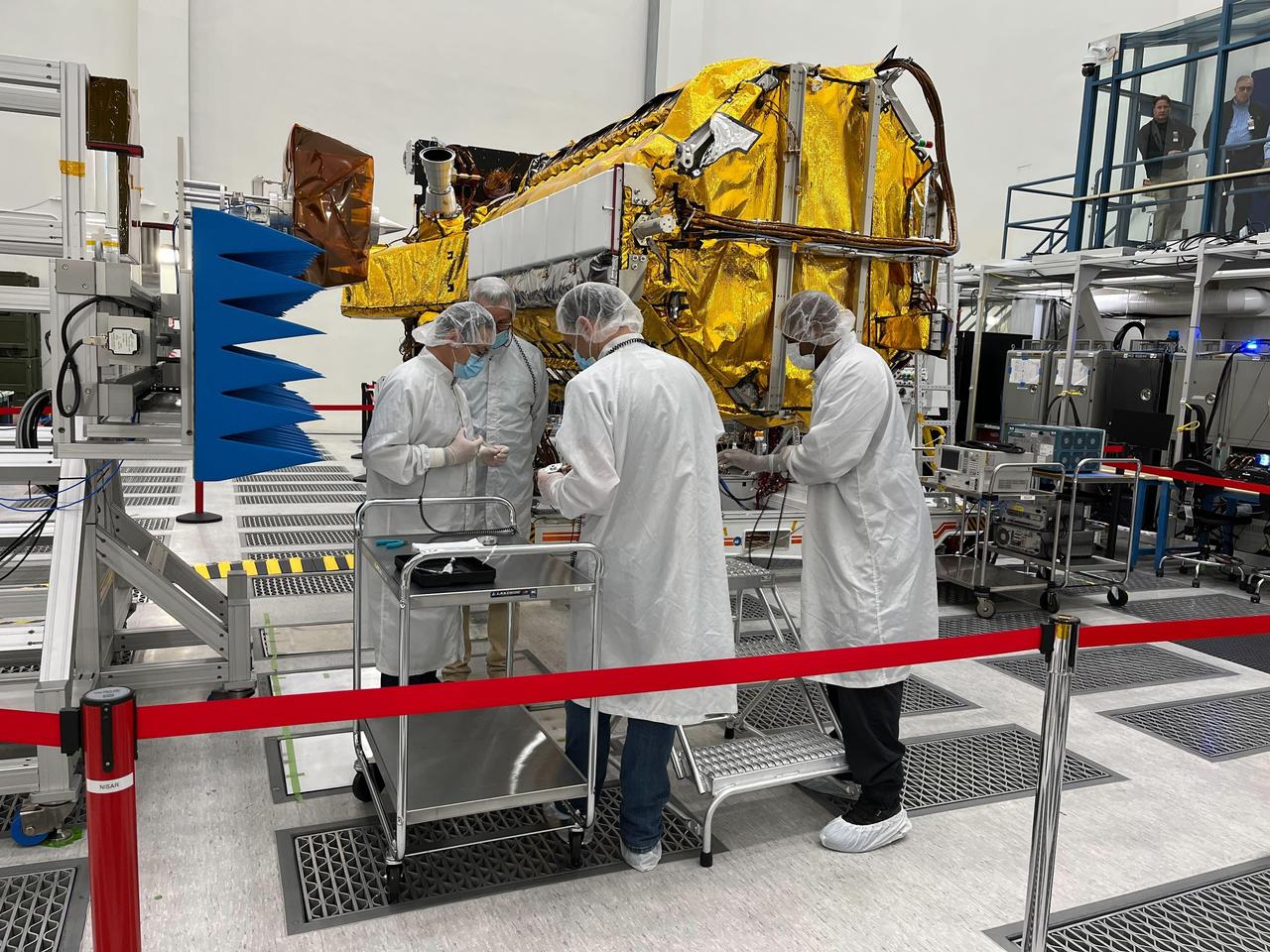 Engineers and technicians from NASA's Jet Propulsion Laboratory work on the NASA-ISRO Synthetic Aperture Radar (NISAR) science instrument payload in a clean room at JPL on Feb. 3, 2023. The payload is scheduled to ship to India in March 2023.      The NISAR mission – a joint effort between NASA and ISRO – will measure changes to Earth's land ice surfaces down to fractions of an inch. Data collected by this satellite will help researchers monitor a wide range of changes critical to life on Earth in unprecedented detail. This includes spotting warning signs of imminent volcanic eruptions, helping to monitor groundwater supplies, tracking the melt rate of ice sheets tied to sea level rise, and observing shifts in the distribution of vegetation around the world. The data will inform humanity's responses to urgent challenges posed by natural disasters and climate change, and help communities prepare for and manage hazards.      There are two instruments on the satellite that will send and receive radar signals to and from Earth's surface to make the mission's measurements. An L-band synthetic aperture radar (SAR), which uses a signal wavelength of around 9 inches (24 centimeters), and an S-band SAR with a signal wavelength of nearly 5 inches (12 centimeters). Both will bounce their microwave signal off of the planet's surface and record how long it takes the signal to make one roundtrip, as well as the strength of that return signal. This enables the researchers to calculate the distance from the spacecraft to Earth's surface and thereby determine how the land or ice is changing. An antenna reflector nearly 40 feet (12 meters) in diameter, supported by a deployable boom, will focus the microwave signals sent and received by the SARs.      JPL, which is managed for NASA by Caltech in Pasadena, leads the U.S. component of NISAR and is providing the mission's L-band SAR instrument. NASA is also providing the radar reflector antenna, the deployable boom, a high-rate communication subsystem for science data, GPS receivers, a solid-state recorder, and payload data subsystem. ISRO is providing the spacecraft bus, the S-band SAR, the launch vehicle, and associated launch services and satellite mission operations.  https://photojournal.jpl.nasa.gov/catalog/PIA25771