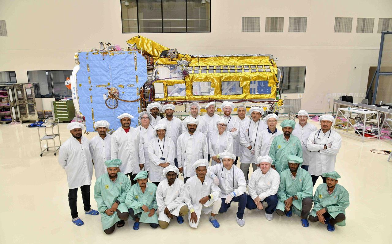 A team of engineers and technicians from the Indian Space Research Organisation and NASA's Jet Propulsion Laboratory in Southern California pose in June at ISRO's U R Rao Satellite Centre (URSC) in Bengaluru, India, after working together to combine the two main components of the NISAR (NASA-ISRO Synthetic Aperture Radar) satellite. Set to launch in early 2024 from the Satish Dhawan Space Centre in Sriharikota, India, NISAR is being jointly developed by NASA and ISRO to observe movements of Earth's land and ice surfaces in extremely fine detail. As NISAR observes nearly every part of Earth at least once every 12 days, the satellite will help scientists understand, among other observables, the dynamics of forests, wetlands, and agricultural lands. The radar instrument payload, partially wrapped in gold-colored thermal blanketing, arrived from JPL in March and consists of L- and S-band radar systems, so named to indicate the wavelengths of their signals. Both sensors can see through clouds and collect data day and night. The bus, which is shown in blue blanketing and includes components and systems developed by both ISRO and JPL, was built at URSC and will provide power, navigation, pointing control, and communications for the mission. The team combined the payload and the bus with the help of a crane. NISAR is an equal collaboration between NASA and ISRO and marks the first time the two agencies have cooperated on hardware development for an Earth-observing mission. JPL, which is managed for NASA by Caltech in Pasadena, leads the U.S. component of the project and is providing the mission's L-band SAR. NASA is also providing the radar reflector antenna, the deployable boom, a high-rate communication subsystem for science data, GPS receivers, a solid-state recorder, and payload data subsystem. URSC, which is leading the ISRO component of the mission, is providing the spacecraft bus, the S-band SAR electronics, the launch vehicle, and associated launch services and satellite mission operations. https://photojournal.jpl.nasa.gov/catalog/PIA25867
