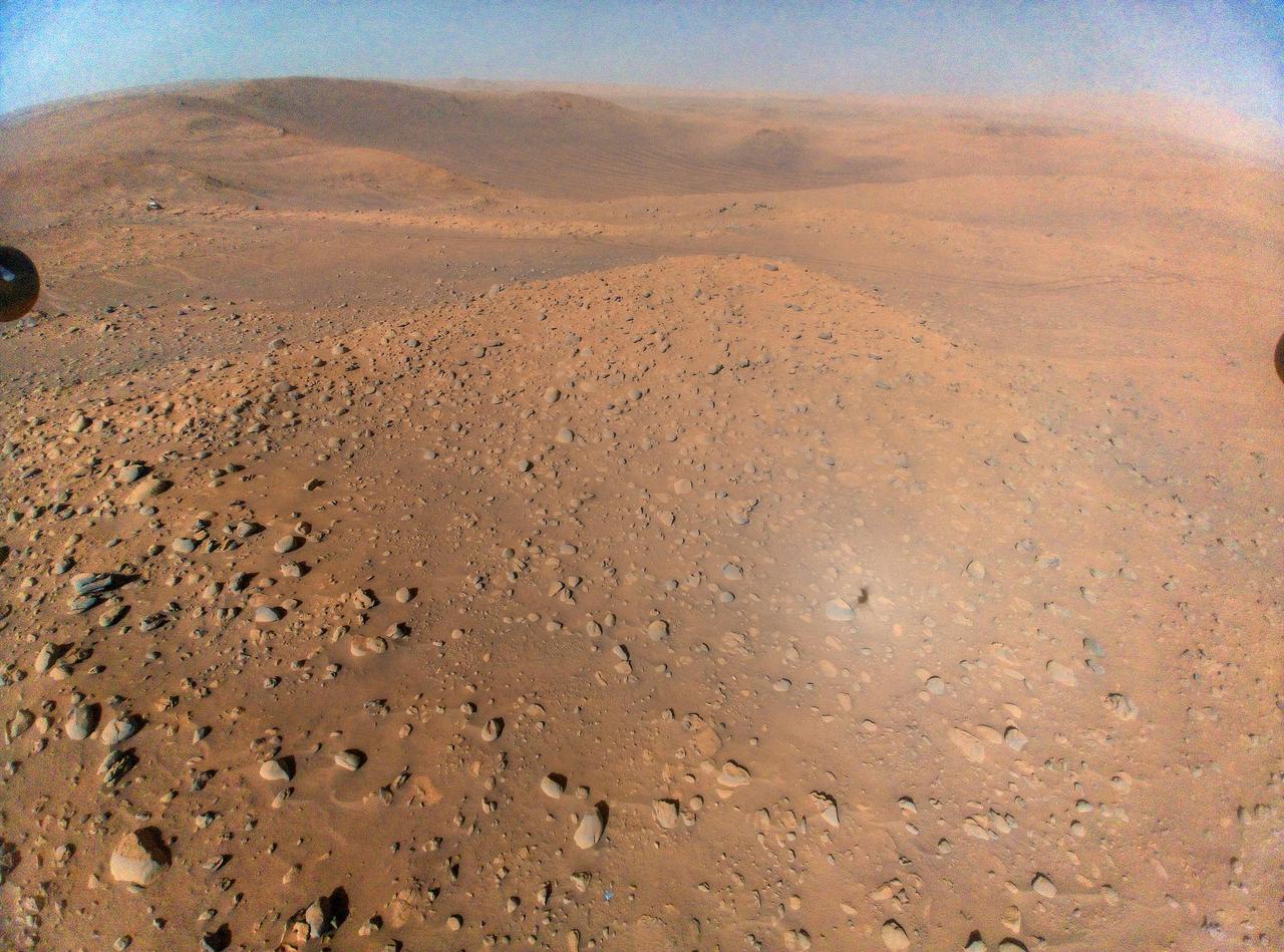 This image of NASA's Perseverance Mars rover at the rim of Belva Crater was taken by the agency's Ingenuity Mars Helicopter during the rotorcraft's 51st flight on April 22, 2023, the 772nd Martian day, or sol, of the rover's mission. At the time the image was taken, the helicopter was at an altitude of about 40 feet (12 meters).  The rover is in the upper left of the image, parked at a light-toned rocky outcrop the science team is calling "Echo Creek." Perseverance's tracks can be seen extending from its location to the upper-right side of image. The helicopter's shadow can be seen on the rocky hill in the foreground, just to the right and below the image's center. The hill, designated "Mount Julian" by the science team, is a planned future stop for the rover. A small triangular piece of debris from the rover's entry, descent, and landing system can be seen at the lower center of image.  https://photojournal.jpl.nasa.gov/catalog/PIA25884