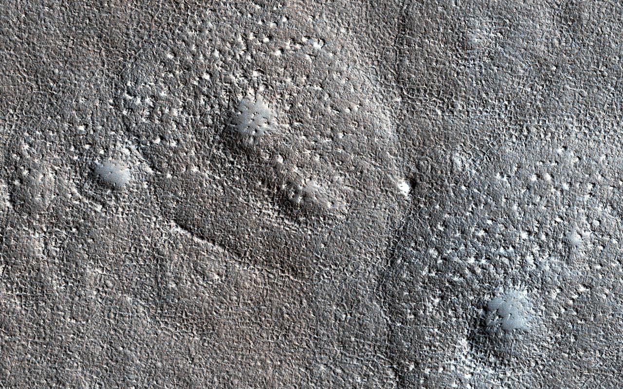 Expanded craters on Mars are thought to occur when the upper slopes of an impact crater in an ice-rich target sublimate (going directly from a solid to a gaseous state). The vaporizing ice makes the walls retreat while the lower slopes are armored by dust and debris, resulting in a funnel-shaped formation. The expanded craters in this image have an unusually bumpy texture in the outer apron where the sublimation occurred. The bumps are too large to be boulders. This suggests that the ice had concentrations of other material. https://photojournal.jpl.nasa.gov/catalog/PIA25900