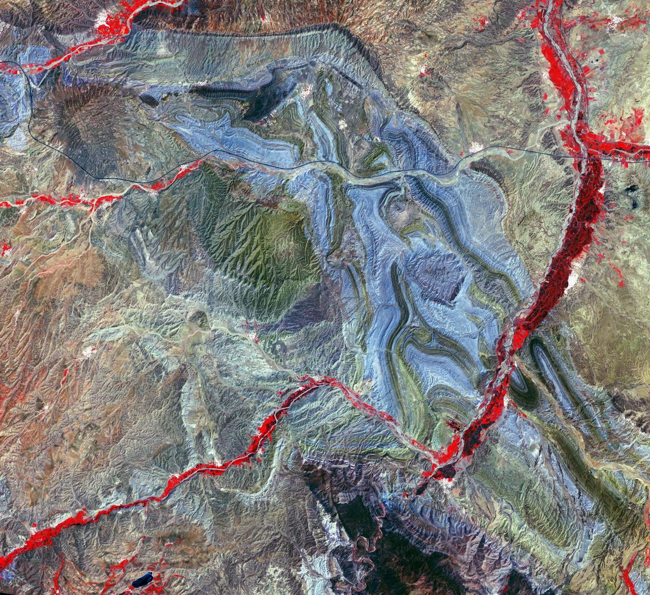 In Iran, near the southwest shore of the Caspian Sea, folded sedimentary rocks are part of the Greater Caucasus Mountain Belt. In false color infrared, the blue colored rocks are white sediments, greenish-toned rocks are redbeds. The vegetated river channel is bright red. The black line going across the image from east to west is Iran Highway 2 that starts in Teheran and ends in Tabriz. The image was acquired June 22, 2020, covers an area of 37.6 by 40.9 km, and is located at 37.1 degrees north, 47.6 degrees east. https://photojournal.jpl.nasa.gov/catalog/PIA25946