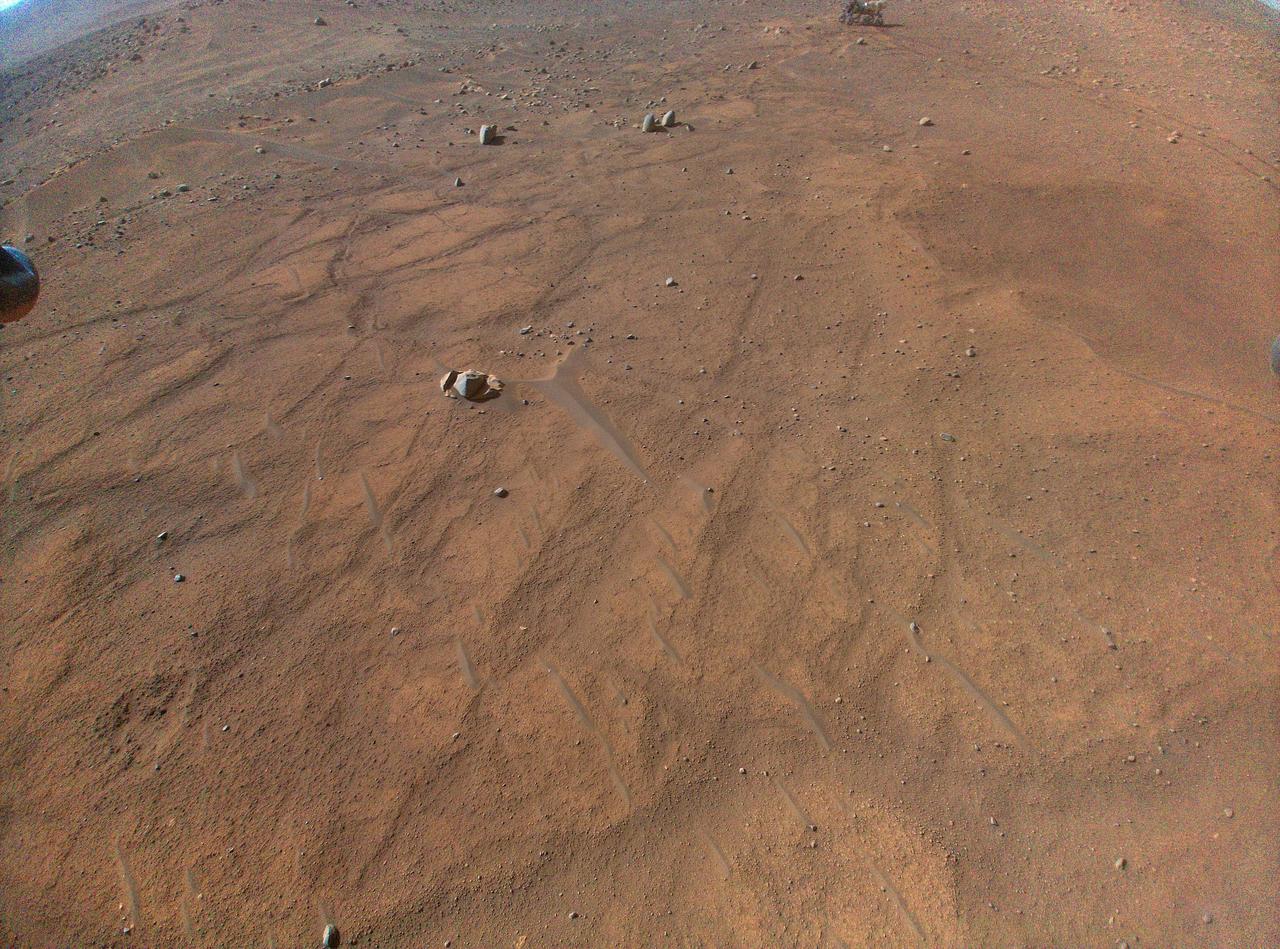 This image of NASA's Perseverance Mars rover – visible at the top, right of center – was taken by the Ingenuity Mars Helicopter during its 54th flight on Aug. 3, 2023, 872nd Martian day, or sol, of the mission. At the time the image was taken, the helicopter was at an altitude of about 16 feet (5 meters).  https://photojournal.jpl.nasa.gov/catalog/PIA25969