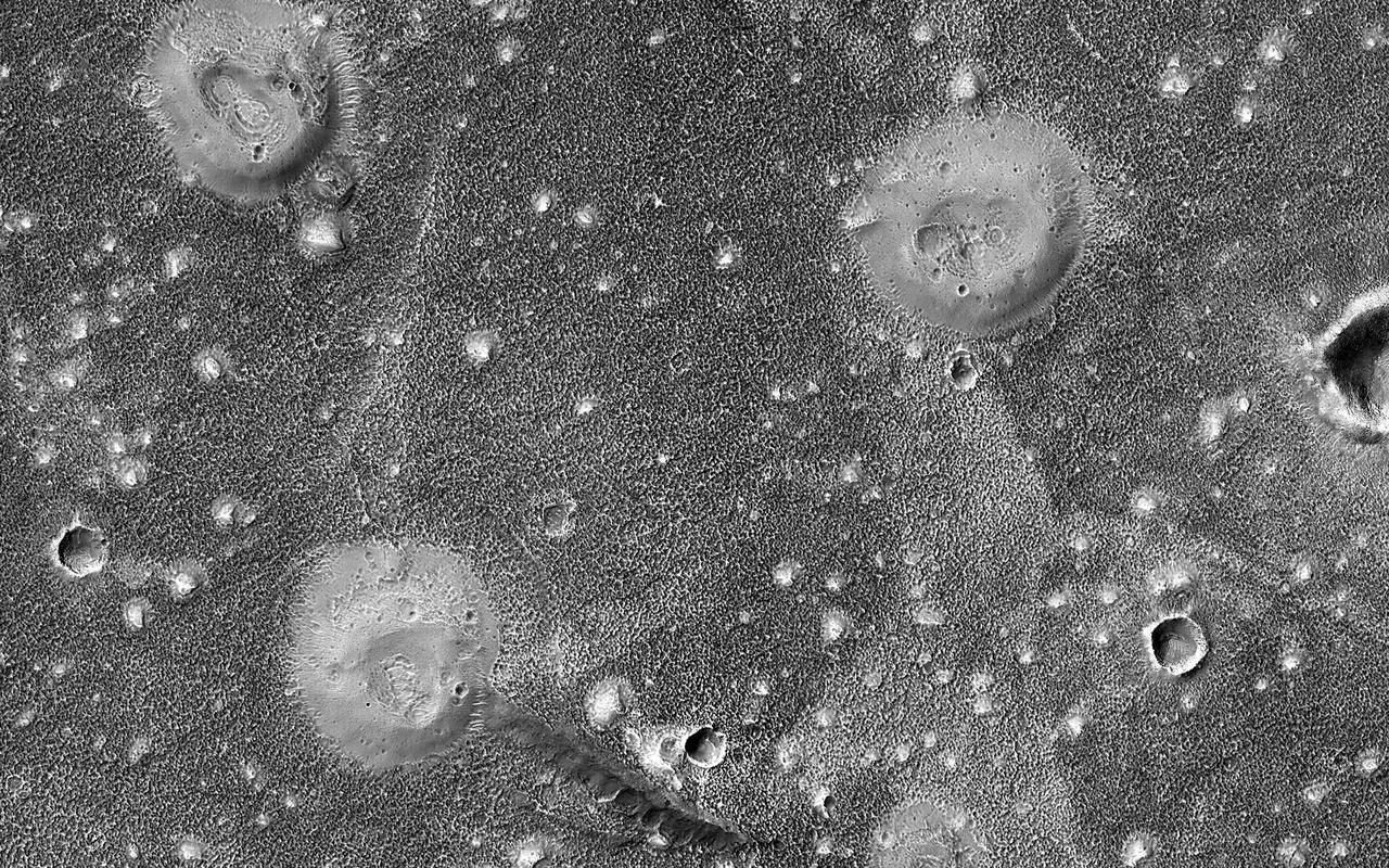 The northern lowlands of Mars in this location are stippled with mounds, such as those visible throughout this image. These lighter-toned circular mounds with bowl-shaped depressions are easy to spot against the darker-toned floor. Scientists think these landforms are similar to mud volcanoes that are also found here on Earth.  Mud volcanoes form as gas and liquid-rich sediment interacts underground. Over time, this slurry of mud is brought to the surface and forms a rounded mound. Scientists are interested in studying mud volcanoes on Mars because the material forming the mound has the potential to be organic in nature and would give insight into possible microbial life below the surface.  https://photojournal.jpl.nasa.gov/catalog/PIA25987
