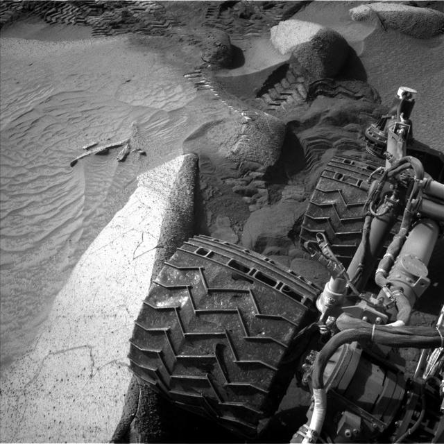 NASA's Curiosity Mars rover captured this image of its right rear wheels using its navigation cameras on June 1, the 3,846th Martian day, or sol, of the mission. The image was taken while the rover was attempting to climb a 23-degree slope covered with slippery sand and wheel-size boulders. Rover tracks from the approach to this location can be seen in the sand at the top of the image. The rover slipped in the sand, causing it to veer off its intended route and prompting its right middle wheel to drive up on to the bright, long rock seen at the left of the image. Driving over this rock was not intended, and the large movement of the suspension triggered a safety fault, stopping the drive. In response, rover planners chose to back away from this spot and try climbing the slope a few feet from here. Curiosity experienced several more faulted drives before a decision was made to pursue a detour on less difficult terrain about 492 feet (150 meters) away. https://photojournal.jpl.nasa.gov/catalog/PIA26016