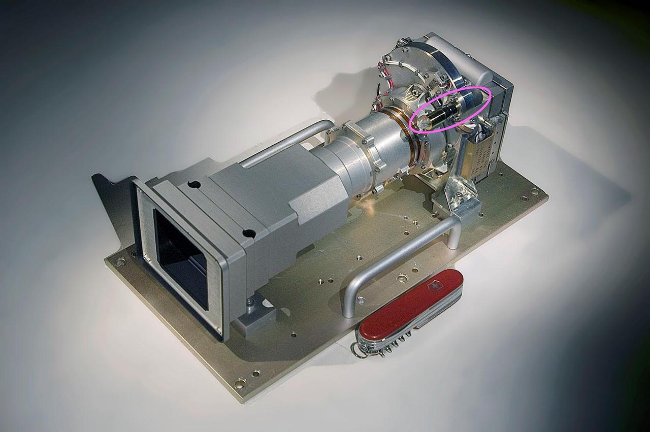 The Mast Camera, or Mastcam, aboard NASA's Curiosity Mars rover is built with two cameras – the left has a 34 mm focal length; the right, a 100 mm focal length. Behind each lens is a rotating wheel (circled in pink) arranged with filters. In addition to providing color images of the rover's surroundings, the cameras and their filters help scientists determine from afar the composition of rocks by the wavelengths of light, or spectra, they reflect in different colors.  On Sept. 19, 2023, the left camera's filter wheel became stuck between the green and clear filter positions, the effects of which can be seen on the mission's raw, or unprocessed, images.  The filter wheel is part of a spur-and-pinion mechanism, with the spur teeth around the filter wheel. The actuation uses a small motor that drives the pinion gear both forward and backward. Despite having been commanded at more than twice its normal torque, this motor has been unable to move in the counterclockwise direction.  If unable to nudge the wheel back to the clear filter, the mission would rely on the higher resolution 100 mm right camera as the primary color-imaging system. The camera needs to take nine times more images than the left to cover the same area, which could affect how the team scouts for science targets and rover routes. The ability to observe detailed color spectra of rocks from afar would also be degraded.  https://photojournal.jpl.nasa.gov/catalog/PIA26043