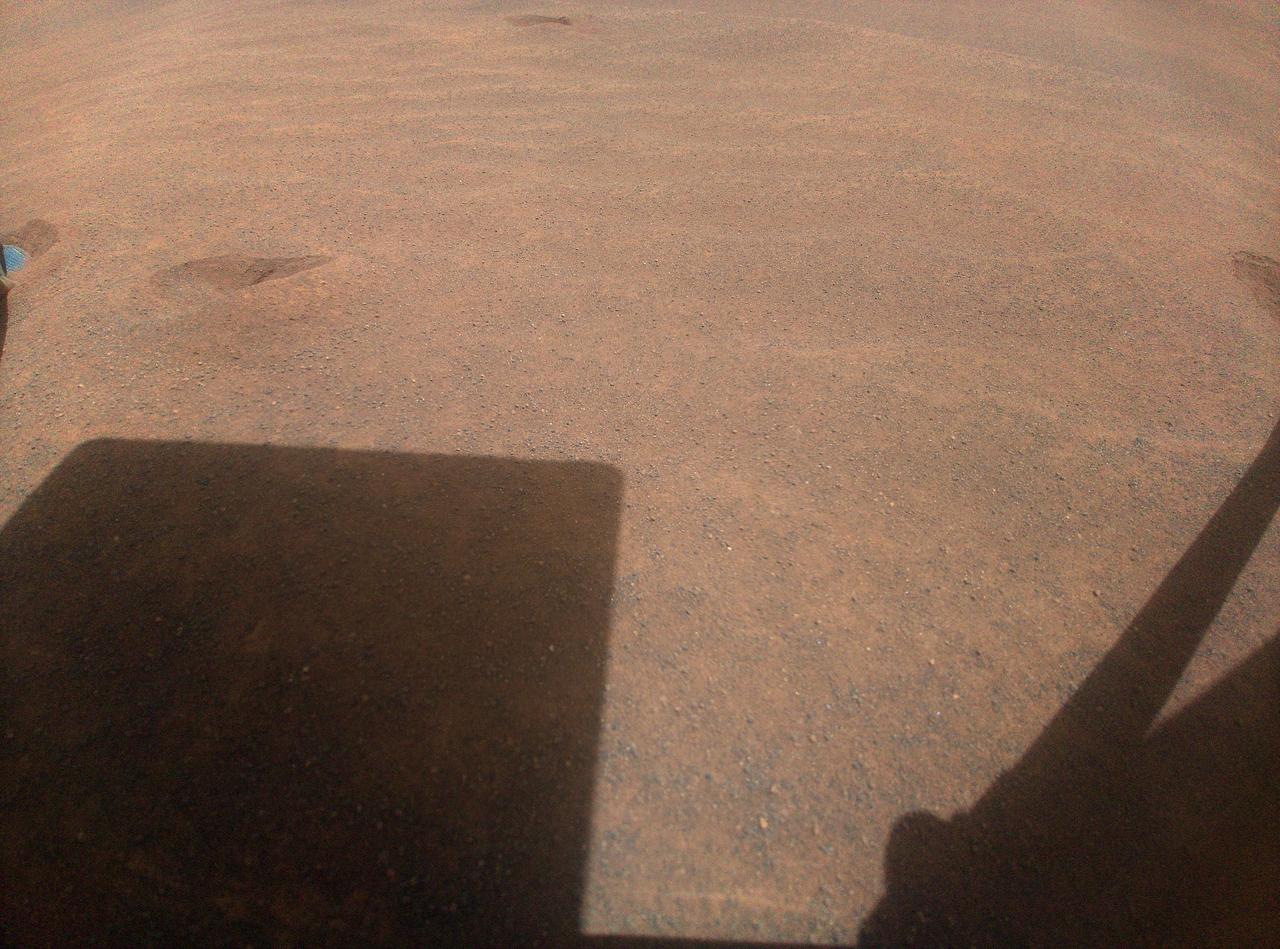 NASA's Ingenuity helicopter captured this view on Nov. 3, 2023, of its parking spot during Mars solar conjunction – a period when the Sun is between Earth and Mars, limiting communications. Ingenuity will use its color camera during this period to take time-lapse images of sand grains to learn more about how they move on the Red Planet. In the upper left of the image, one of the helicopter's legs is visible just out of frame. Just to the right of that is one of several "footprints" made before the helicopter lifted off on a previous flight to reposition itself.  During conjunction, hot, ionized gas being expelled from the Sun's corona can potentially corrupt radio signals sent from Earth to NASA's fleet of Mars spacecraft, leading to unexpected behaviors. So, during this time, engineers don't send any commands, but the spacecraft do send their health data back to Earth.  After conjunction, scientists will look through Ingenuity's imagery and see if any sand grains were blown by the wind. They plan to correlate this imagery with weather data collected by NASA's Perseverance rover, which is parked 3,471 feet (1,058 meters) away during conjunction. Wind and sand are major drivers of change on the Martian landscape, and scientists hope they will better understand these processes by studying the wind strength needed to lift sand particles.  https://photojournal.jpl.nasa.gov/catalog/PIA26050