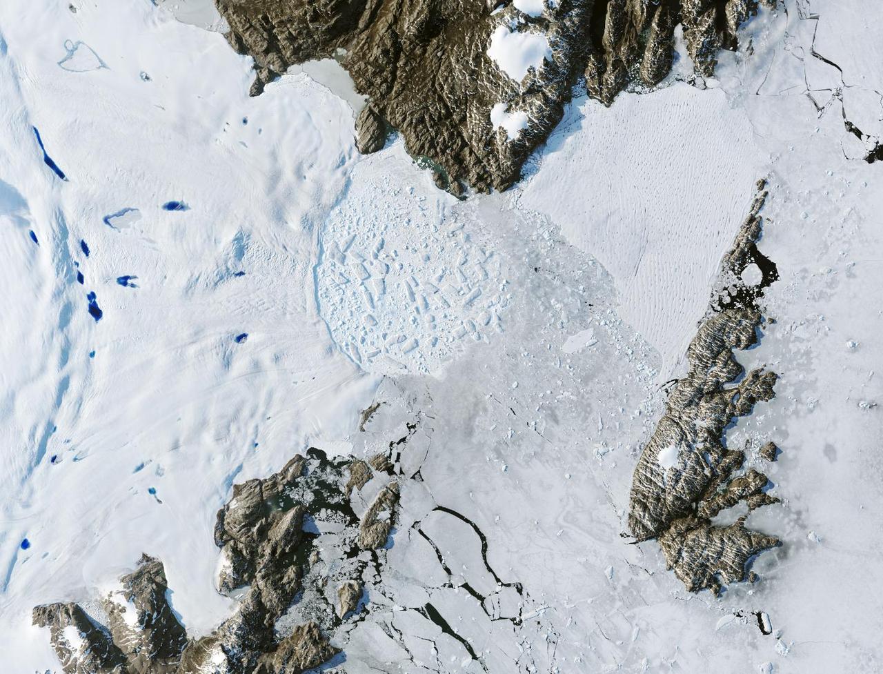Satellite images from 2022 (Main image) and 1999 (Figure A) capture the retreat of Zachariae Isstrom, a glacier in northeast Greenland, as icebergs broke off its edge over the course of 23 years. In a recent study in Nature, researchers from NASA's Jet Propulsion Laboratory in Southern California calculated that Zachariae lost an estimated 176 billion tons (160 billion metric tons) of ice in the period between 1985 and 2022. That was the greatest mass lost for the period of any of the 207 glaciers analyzed in the paper.  The earlier image was taken by the Enhanced Thematic Mapper Plus on the Landsat 7 satellite on Aug. 5, 1999, while the later image was captured by the Operational Land Imager on the Landsat 8 satellite on Aug. 22, 2022.  The study took a comprehensive look at glacial retreat around the edges of the entire Greenland Ice Sheet from 1985 to 2022 and found that 179 glaciers retreated significantly since 1985, 27 held steady, and just one advanced slightly.  The study found that overall the ice sheet shed about 1,140 billion tons (1,034 billion metric tons) of ice from 1985 to 2022, one-fifth more mass than previously estimated, as icebergs fell into the ocean at an accelerating rate.  Most of the ice loss came from below sea level, in fjords on Greenland's periphery. Once occupied by ancient glacial ice, many of these deep coastal valleys have filled with seawater – meaning the ice that broke off made little net contribution to sea level. But the loss likely accelerated the movement of ice flowing down from higher elevations, which in turn added to sea level rise. It also added previously unaccounted-for fresh water to the North Atlantic Ocean, which could have impacts on global ocean currents.  https://photojournal.jpl.nasa.gov/catalog/PIA26118