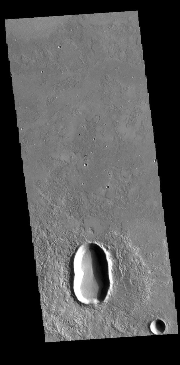This unnamed crater in Utopia Planitia is shaped like a peanut shell, with an indentation in the crater rim at the middle of the crater. It is likely that this crater was created by a dual impact. In a dual (or double) impact the incoming meteor is broken into two or more pieces which impact together into the surface. This type of impact often has a unique ejecta blanket shape, pinched at the center making a butterfly shape, and a pronounced inner rim jutting out at the center. The ejecta blanket in this case does not show the butterfly shape, and the middle rim is on slightly visible on the left side of the crater. These irregularities may indicate the the meteor pieces were still very close together when they hit the surface. Orbit Number: 95144 Latitude: 31.6611 Longitude: 128.303 Instrument: VIS Captured: 2023-05-27 11:12 https://photojournal.jpl.nasa.gov/catalog/PIA26261