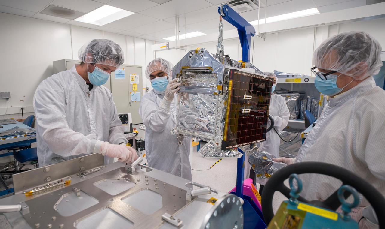 In a clean room at NASA's Jet Propulsion Laboratory in Southern California in March 2024, engineers and technicians prepare the agency's Farside Seismic Suite (FSS) for testing.  The cube-shaped payload contains two instruments that will gather NASA's first seismic data from the Moon in nearly 50 years and take the first-ever seismic measurements from the Moon's far side. FSS will operate continuously for at least 4½ months, working through the long, cold lunar nights.  Here, engineers move FSS onto a fixture that will allow them to tilt the payload, simulating the pull of lunar gravity in the direction at which one of the instrument's two seismometers is sensitive to motion. (The Moon's gravity is about one-sixth of Earth's.) Called an ambient tilt test, this activity allows engineers to check the seismometers' performance.  The two seismometers are packaged together with a large battery, a computer, and electronics inside a cube structure that's surrounded by several layers of insulation and suspended within an outer protective cube, which is in turn covered with a shiny insulating blanket. The suite's single solar panel can be seen right of center.  Surrounding the instrument are (from left): Nik Schwarz, Vik Singh, Joanna Farias, and Bert Turney.  https://photojournal.jpl.nasa.gov/catalog/PIA26298