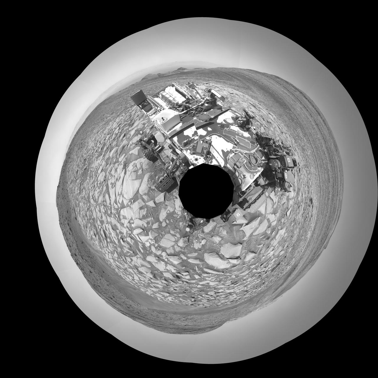 NASA's Curiosity Mars rover captured this selfie using its left black-and-white navigation camera, which is mounted on its mast, or "head," on Feb. 3, 2024, the 4,086th Martian day, or sol, of the mission. The selfie is made up of 36 individual images that were stitched together after being sent back to Earth.  This warped view is different than the color selfies Curiosity has taken in the past using the camera on the end of its robotic arm, called the Mars Hand Lens Imager, or MAHLI. With its arm acting as a kind of selfie stick, Curiosity can show more of its body and surroundings.  Instead, the images from the navigation camera on the mast are displayed as a polar projection; the black hole in the center is where the mast is located on the rover, an area which it can't image.  https://photojournal.jpl.nasa.gov/catalog/PIA26310