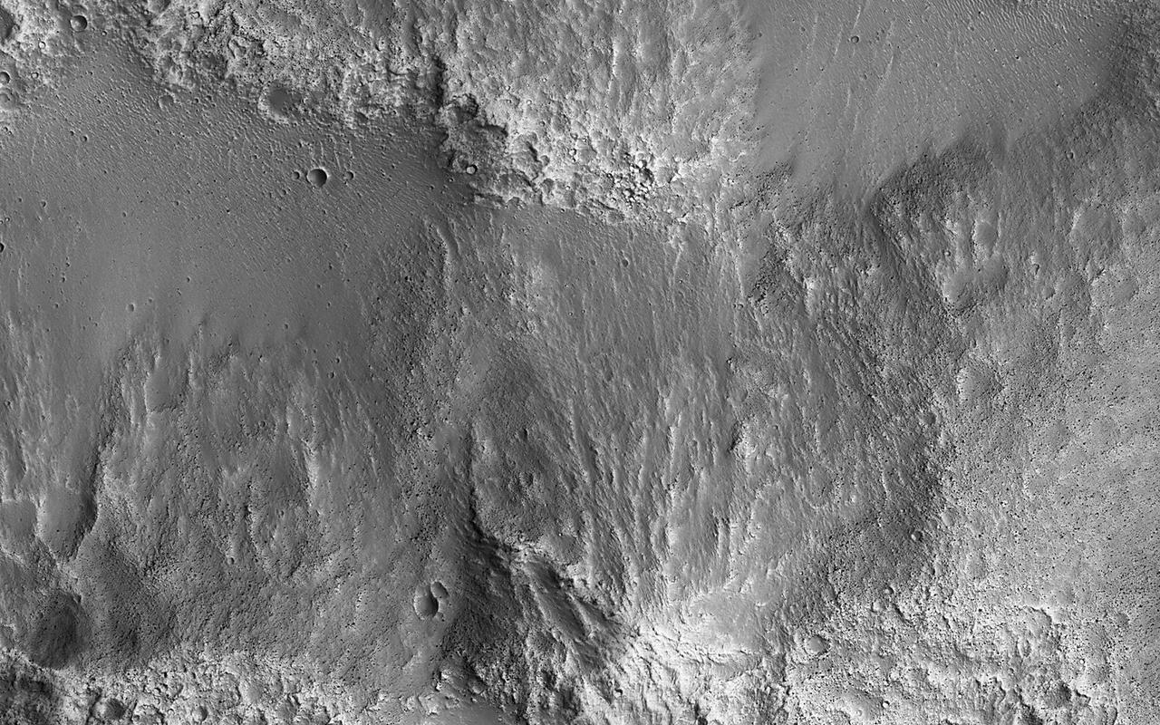 This survey of the canyon floor of Tithonium Chasma in Valles Marineris reveals terrain of two distinct ages. The slopes and hilltops here are made up of rough rocky outcrop that was sculpted by impact craters of all sizes. In contrast, the valley floors are filled with light toned, smooth materials with far fewer large craters. At HiRISE resolution, we can see that the "smooth" materials are in fact littered with boulders and small impact craters, so they cannot have been emplaced very recently. However, the absence of larger craters tells us that the smooth materials are much younger than the ancient rocky outcrops of the canyon floor. The smooth materials appear to be sediments that were deposited possibly by the wind, long after the canyon was formed. The sediments filled in the low lying spots in the canyon floor, leaving a landscape that resembles lakes and ponds but is made up of dust and sand instead of water. https://photojournal.jpl.nasa.gov/catalog/PIA26328
