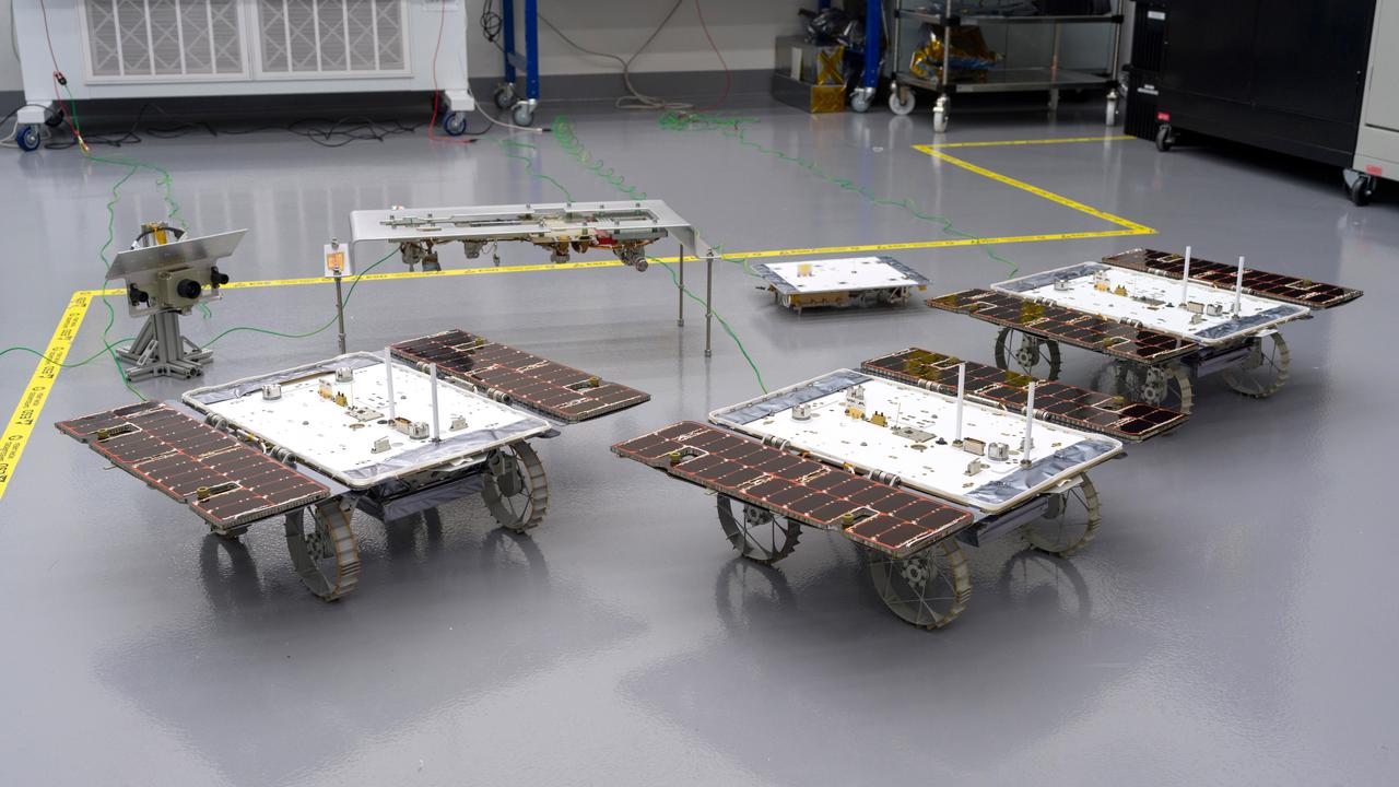 Three small rovers bound for the Moon – part of NASA's CADRE (Cooperative Autonomous Distributed Robotic Exploration) technology demonstration – are arrayed in a clean room at the agency's Jet Propulsion Laboratory in Southern California on Jan. 26, 2024.  CADRE is designed to show that a group of robotic spacecraft can work together autonomously as a team to accomplish tasks and record data without constant direction from mission controllers on Earth.  Each about the size of a carry-on suitcase, the rovers will ride to the Moon's surface aboard a lander equipped with the hardware elements that sit behind them in this image: from left, the situational awareness camera assembly, one of the deployers that will lower the rovers onto the lunar surface, and the base station with which the rovers will communicate via mesh network radios.  https://photojournal.jpl.nasa.gov/catalog/PIA26346