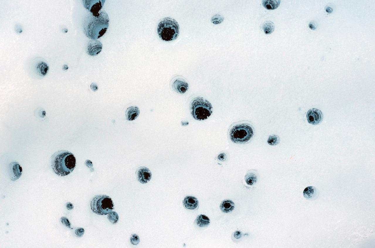 These holes, captured on Alaska's Matanuska Glacier in July 2012, are formed by cryoconite – dust particles that melt into the ice over time, eventually forming small pockets of water below the glacier's surface. Scientists believe similar pockets of water – called cryoconite holes on Earth – could form within dusty water ice on Mars.  https://photojournal.jpl.nasa.gov/catalog/PIA26409