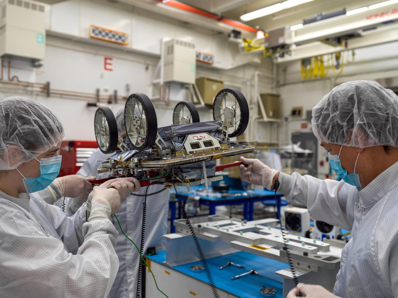 One of three small lunar rovers that are part of a NASA technology demonstration called CADRE (Cooperative Autonomous Distributed Robotic Exploration) is prepared for shipping in a clean room at the agency's Jet Propulsion Laboratory in Southern California on Jan. 29, 2025. CADRE aims to prove that a group of robots can collaborate to gather data without receiving direct commands from mission controllers on Earth. Its trio of rovers will use their cameras and ground-penetrating radars to send back imagery of the lunar surface and subsurface while testing out the novel software systems that enable them to work together as a team autonomously. Before embarking on the first leg of a multistage journey to the Moon, each rover was mated to its deployer system, which will lower it via tether from an Intuitive Machines lander onto the dusty lunar surface. Engineers flipped each rover-deployer pair over and attached it to an aluminum plate for safe transit. The rovers were then sealed into protective metal-frame enclosures that were fitted snuggly into metal shipping containers and loaded onto a truck for the drive to Intuitive Machines' Houston facility. Here, members of the project's assembly, test, and launch operations team hold the upside-down rover by temporary red handles in order to move it to a table where they'll attach it to the aluminum plate. A division of Caltech in Pasadena, California, JPL manages CADRE for the Game Changing Development program within NASA's Space Technology Mission Directorate in Washington. The technology demonstration was selected under the agency's Lunar Surface Innovation Initiative, which was established to expedite the development of technologies for sustained presence on the lunar surface. CADRE will launch as a payload on the third lunar lander mission by Intuitive Machines, called IM-3, under NASA's CLPS (Commercial Lunar Payload Services) initiative, which is managed by the agency's Science Mission Directorate, also in Washington. The agency's Glenn Research Center in Cleveland and its Ames Research Center in Silicon Valley, California, both supported the project. Motiv Space Systems designed and built key hardware elements at the company's Pasadena facility. Clemson University in South Carolina contributed research in support of the project. For more about CADRE, go to: https://go.nasa.gov/cadre https://photojournal.jpl.nasa.gov/catalog/PIA26427